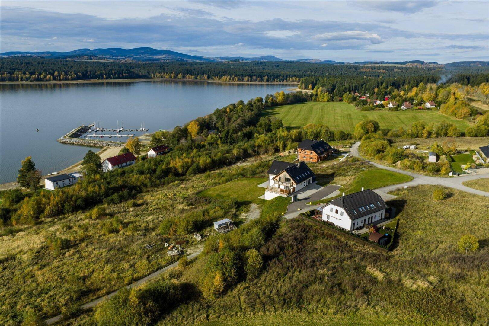 Luftaufnahme der Seenlandschaft mit mehreren Häusern und weitläufigen Grünflächen.