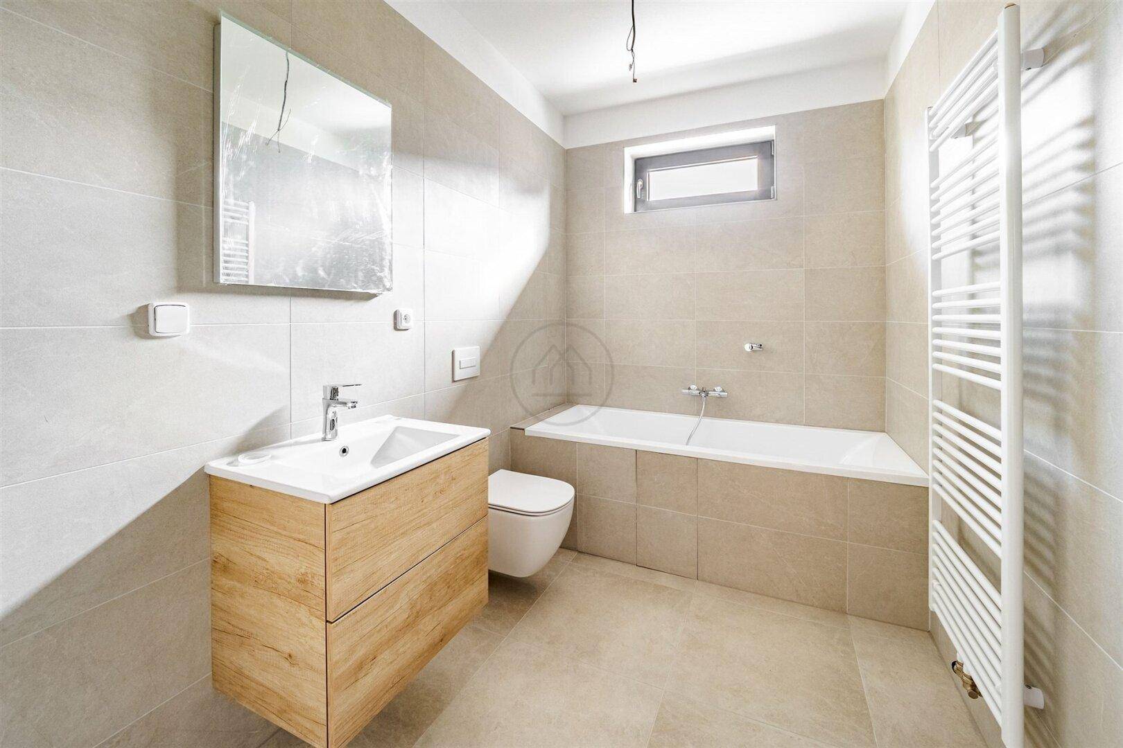 Modernes Badezimmer mit Badewanne, Waschtisch und beheiztem Handtuchhalter.