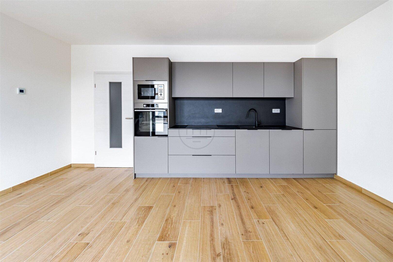 Moderne Einbauküche in Grau mit integrierten Geräten und Holzboden.