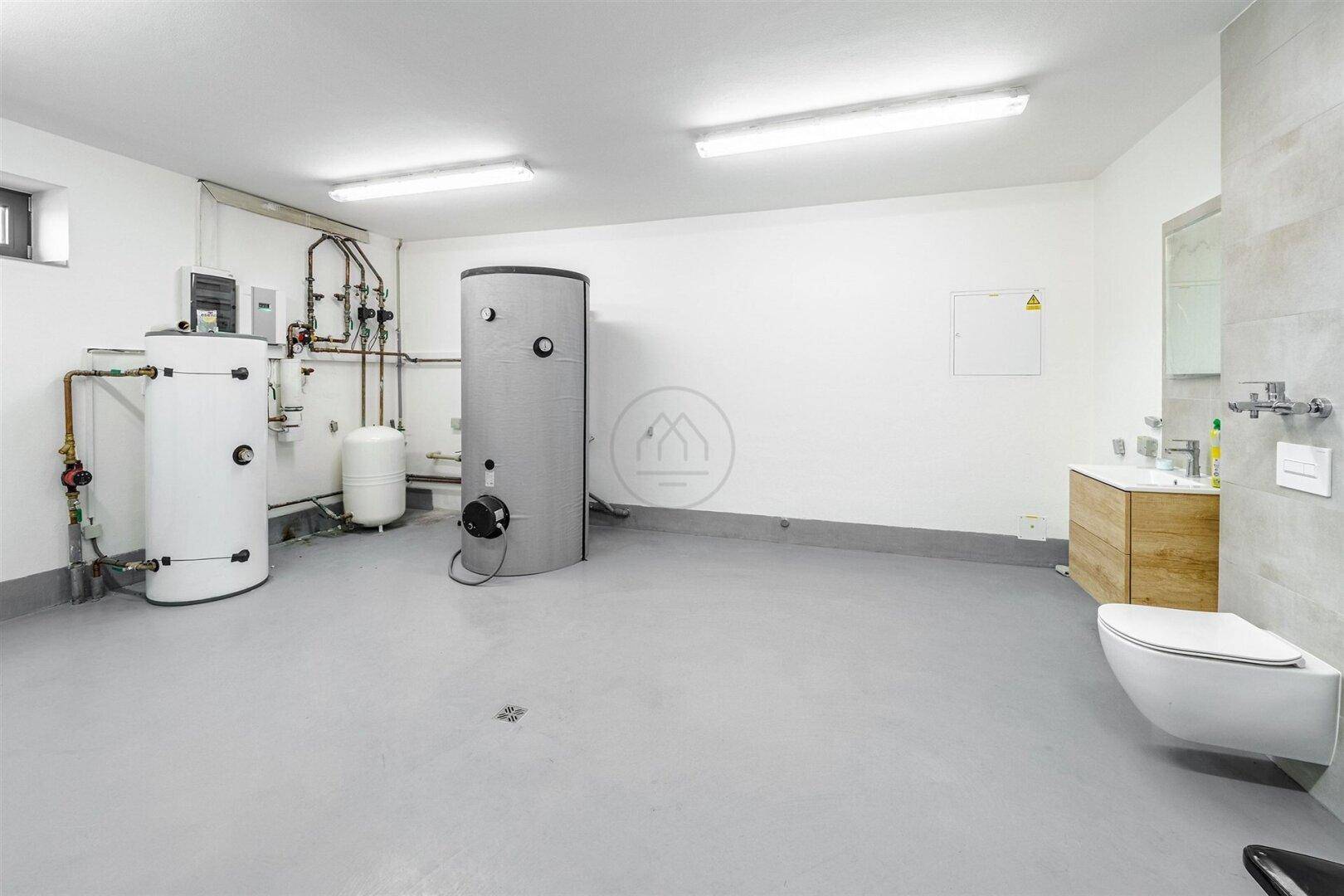 Technikraum mit Warmwasserspeichern, Heizungsinstallationen und separatem WC.