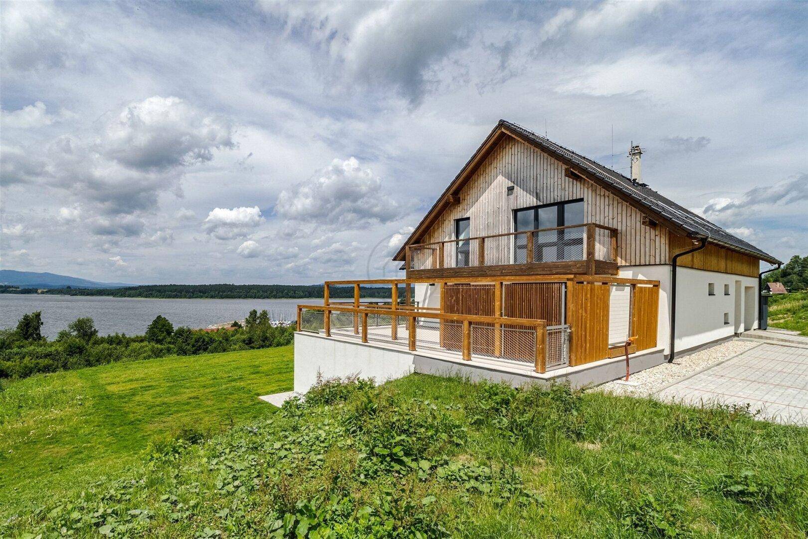 Hausfassade mit Holzverkleidung und großer Terrasse mit Seeblick.