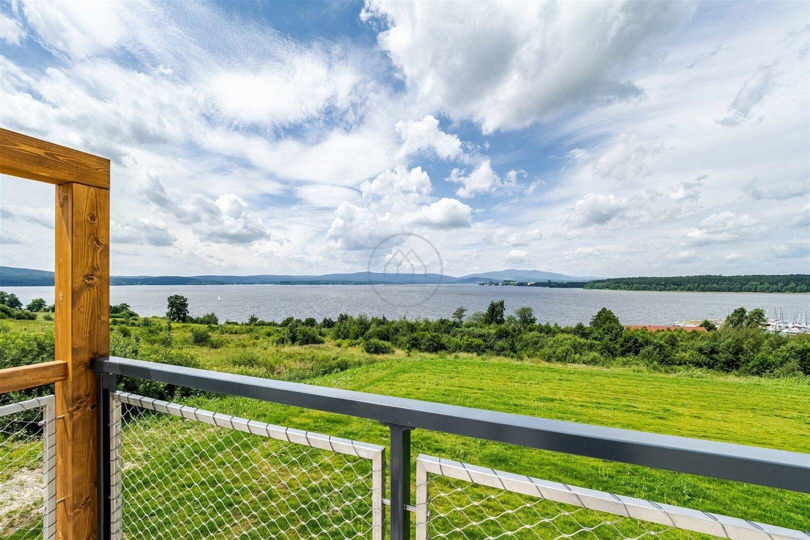 Balkon mit Metallgeländer und weitem Blick über den See und die Landschaft.