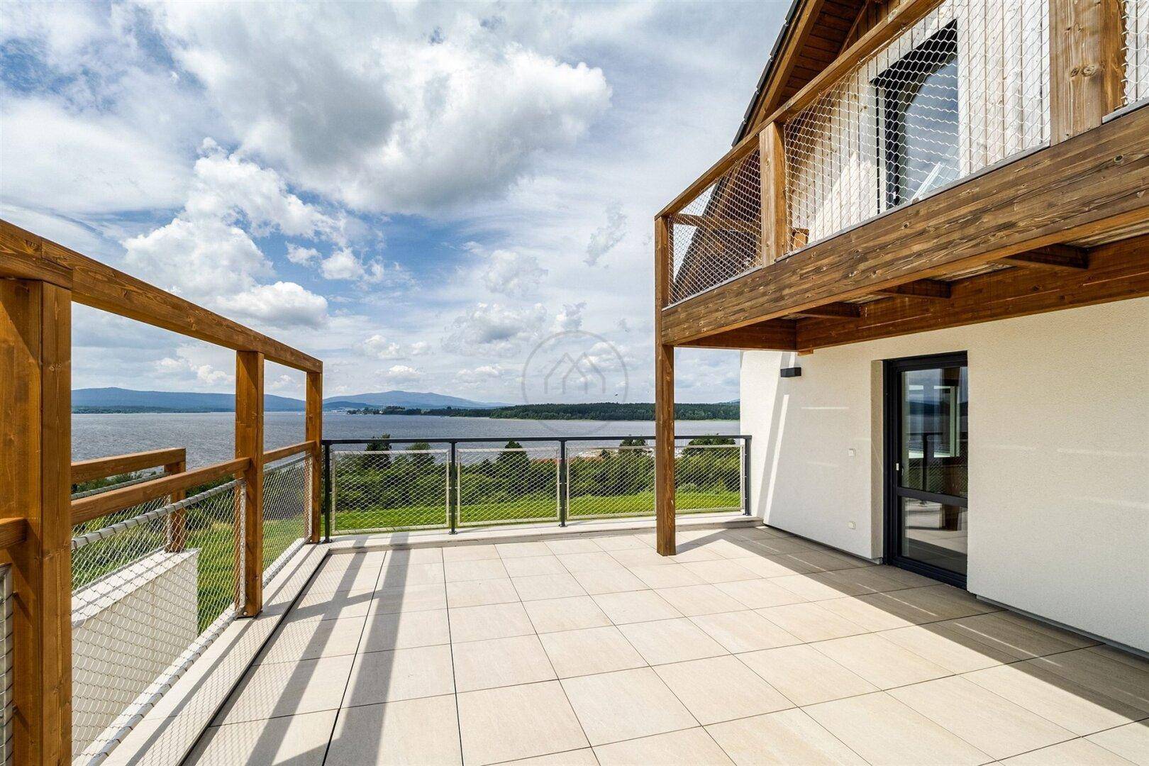 Große Terrasse mit Fliesenboden und Geländer, bietet weiten Seeblick.