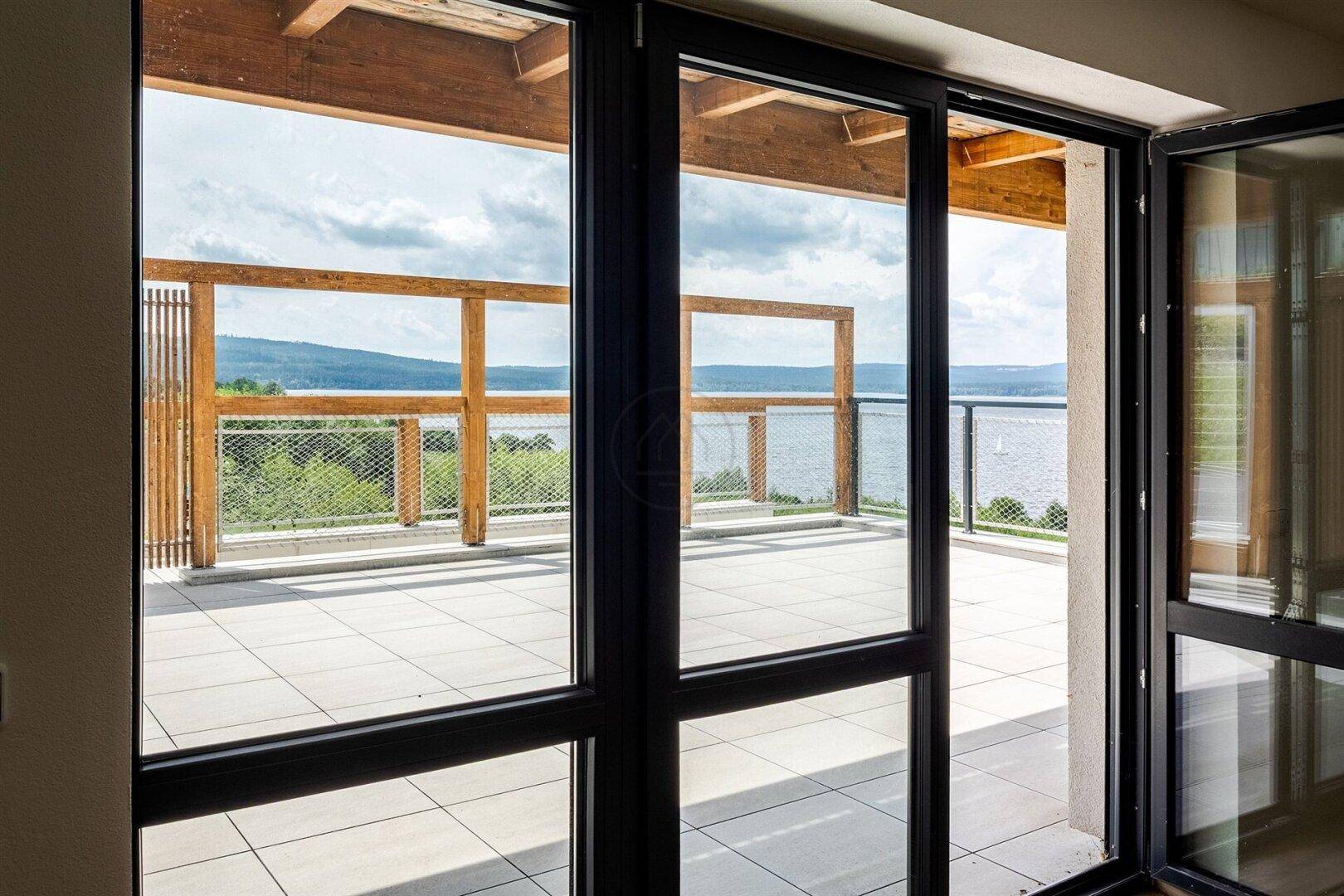 Große Fensterfront bietet Zugang zur Terrasse und weiten Seeblick.