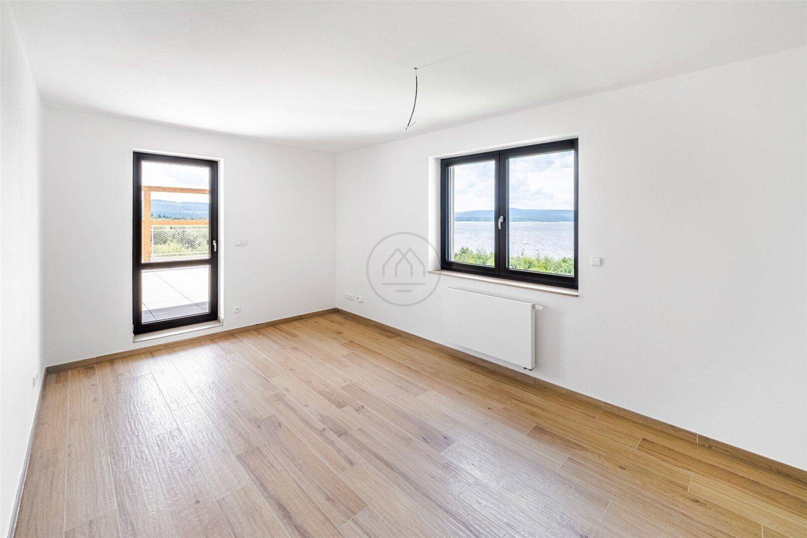 Heller Raum mit Seeblick, Holzboden und großem Fenster.