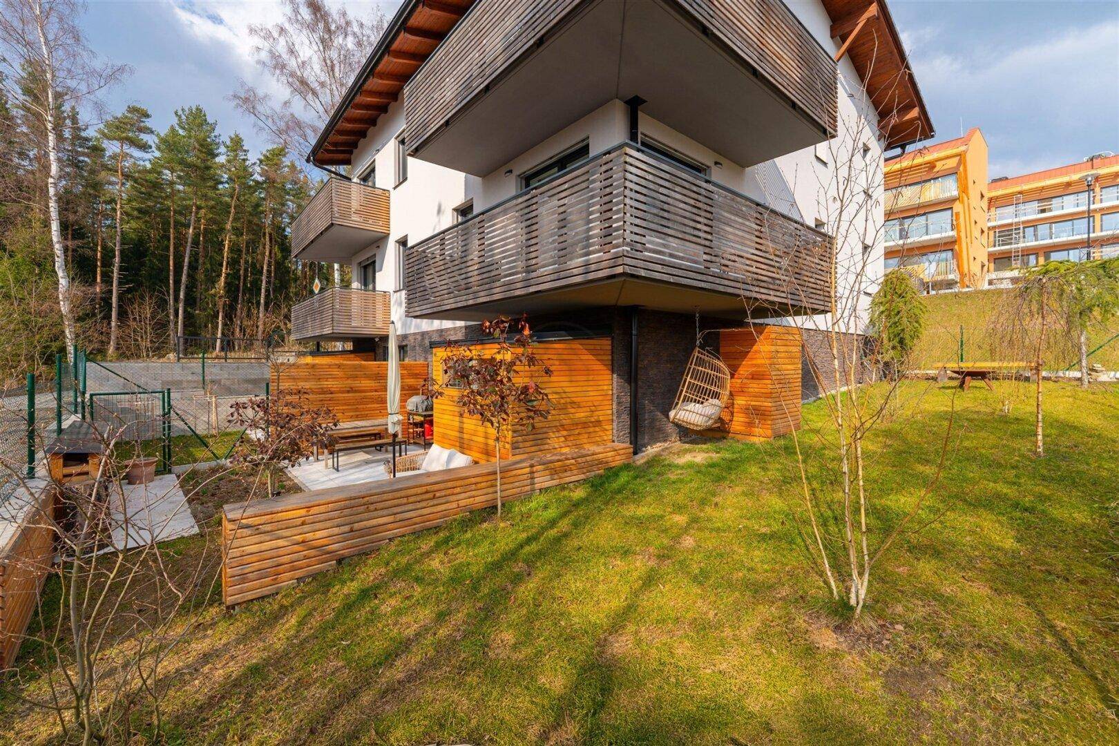 Gebäudeseite mit Balkonen, Grünfläche und Blick auf die umliegende Landschaft.