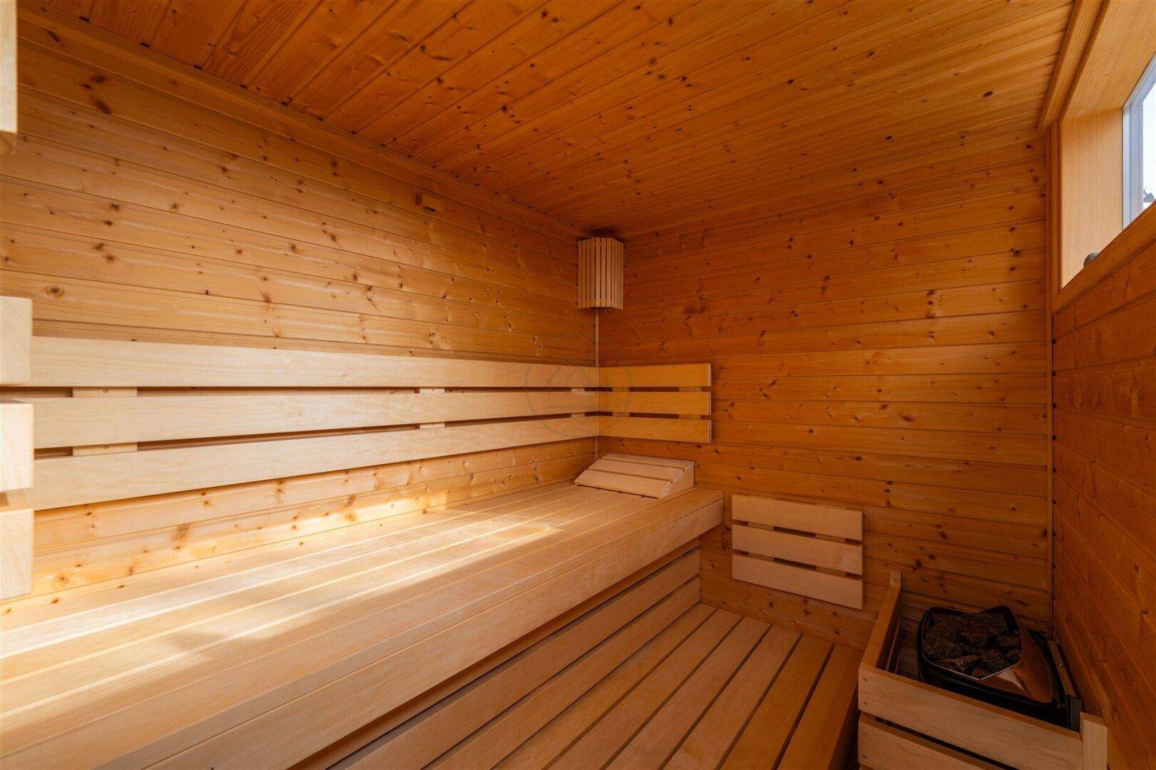 Innenansicht der Holzsauna mit Bänken und traditionellem Saunaofen.