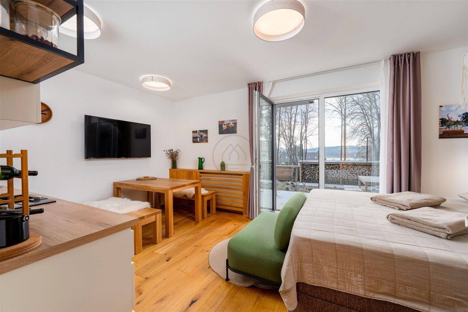 Gemütlicher Wohnbereich mit Esstisch, Fernseher und Blick auf die umliegende Landschaft.