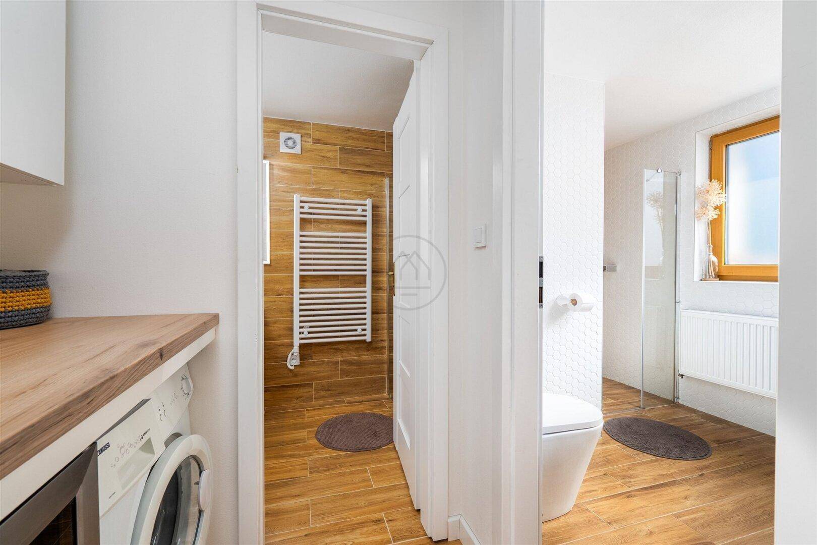 Praktischer Hauswirtschaftsraum mit Waschmaschine, Arbeitsplatte und Zugang zum Badezimmer.