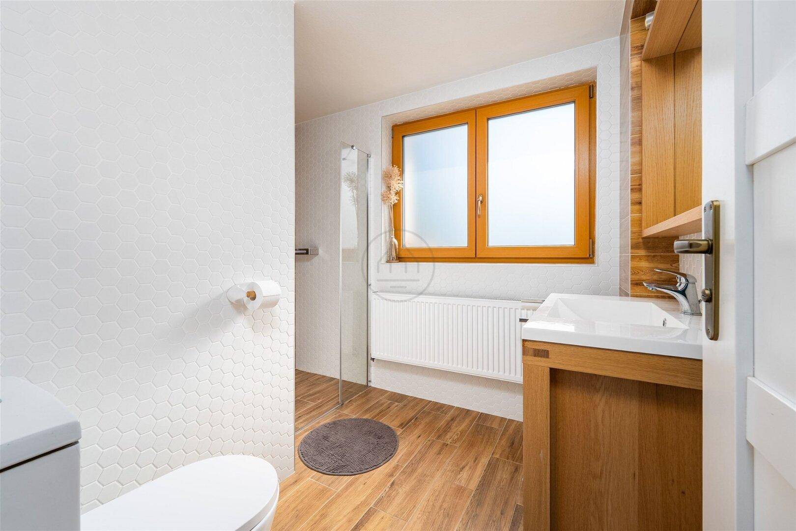 Modernes Badezimmer mit Duschkabine, Holzoptikfliesen und Fenster für Tageslicht.