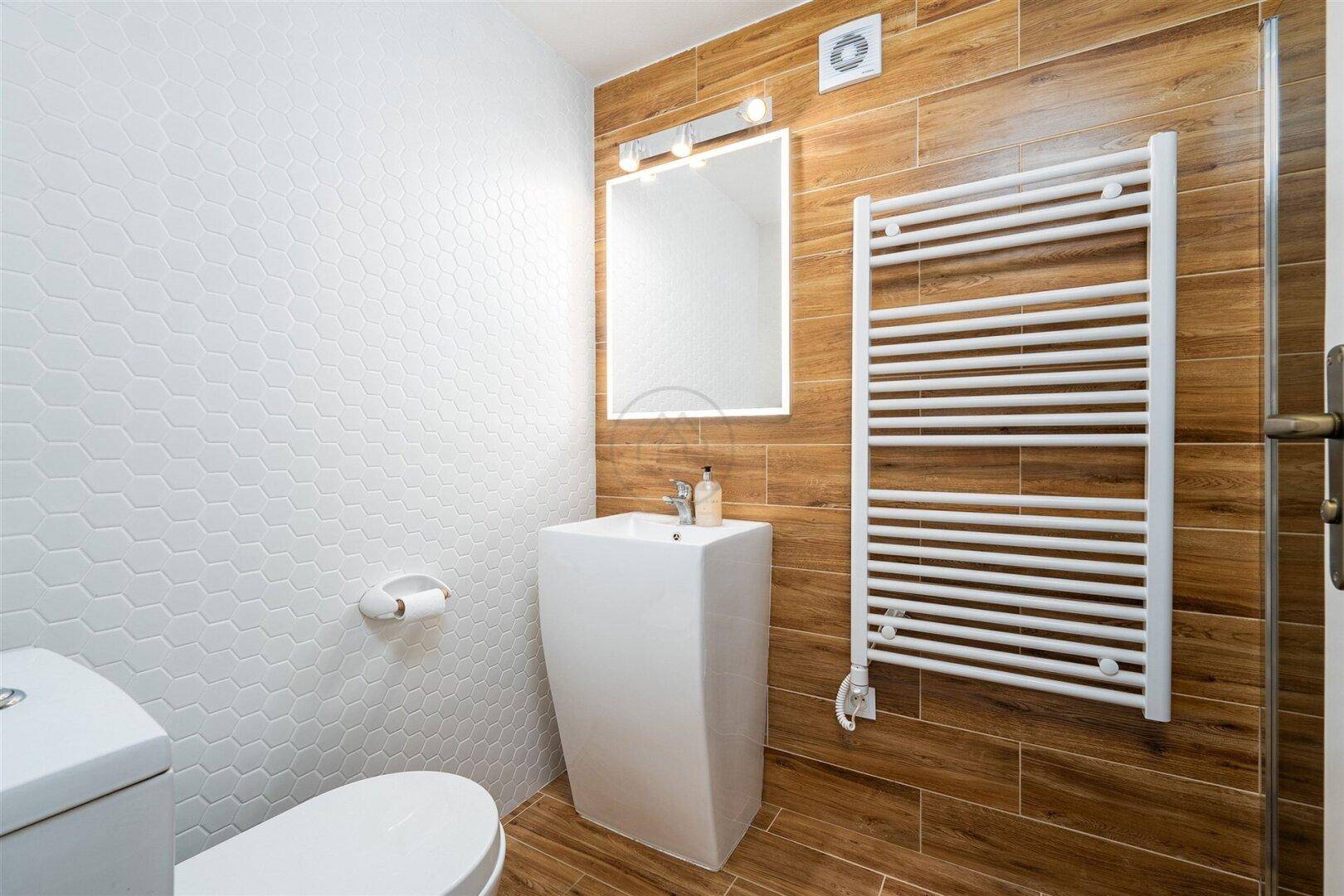 Kleines modernes Badezimmer mit Standwaschbecken, WC und Heizkörper.