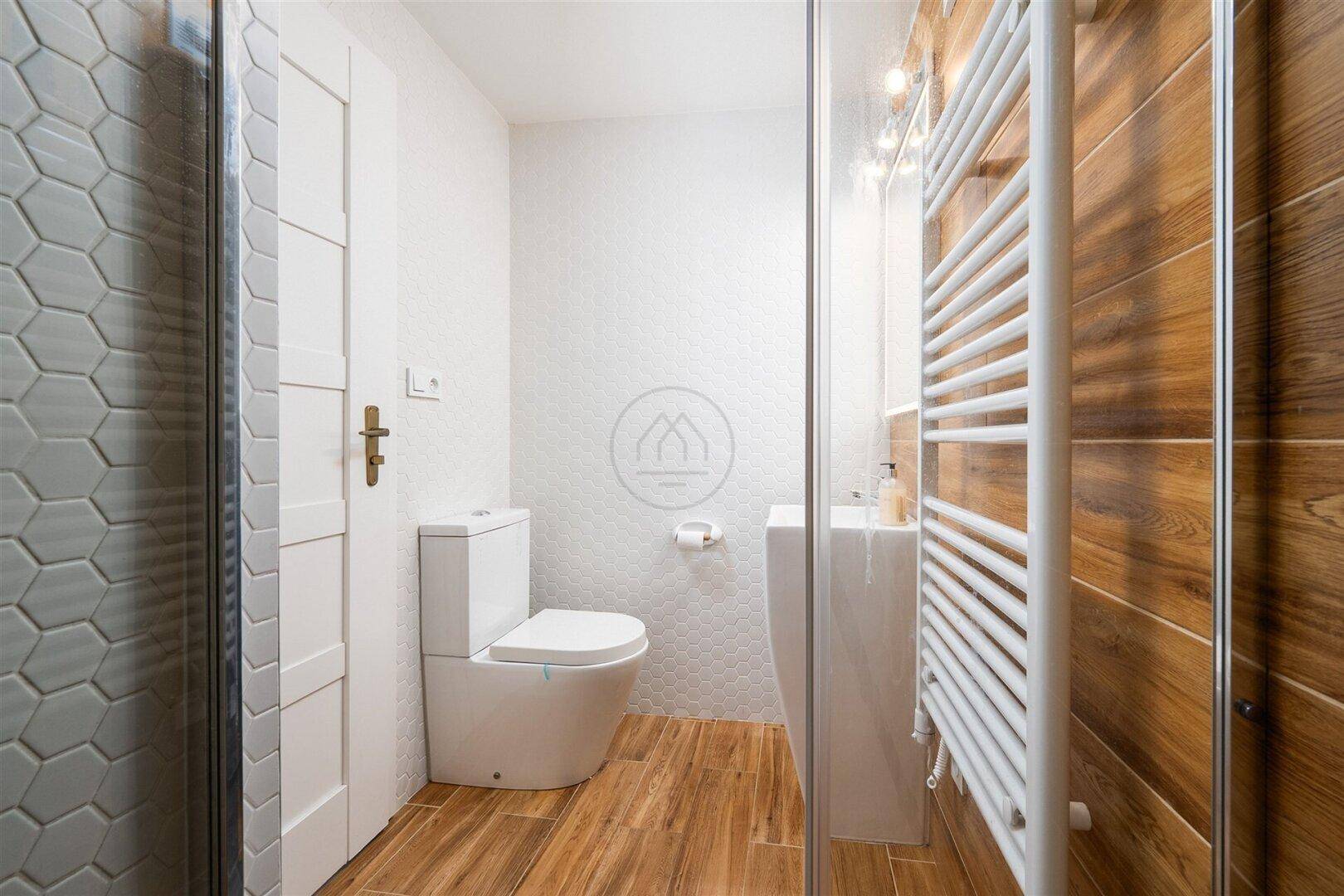 Modernes Badezimmer mit Duschkabine, WC und Heizkörper an der Wand.