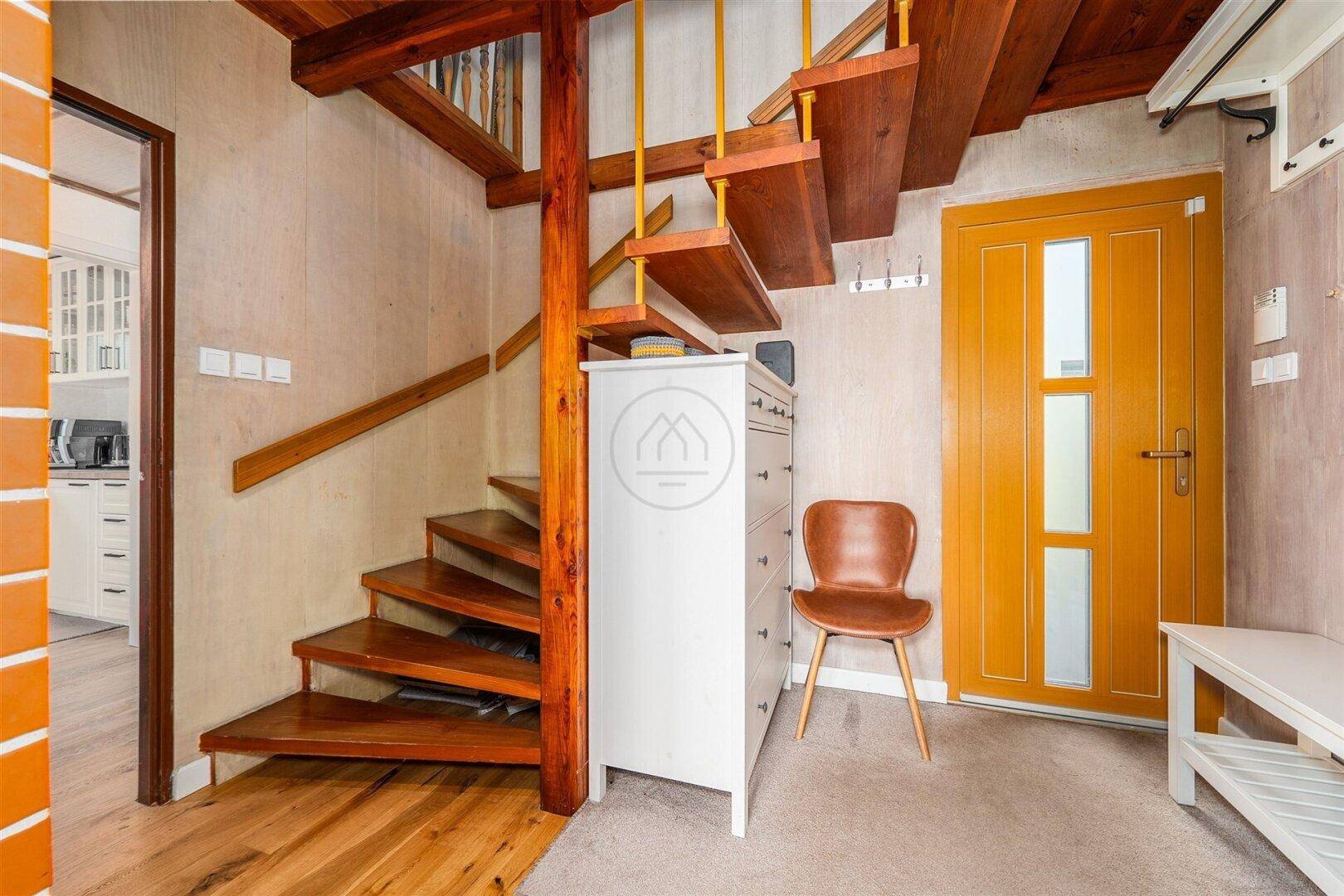 Eingangsbereich mit Holztreppe, die in die oberen Stockwerke führt, und gelber Tür.