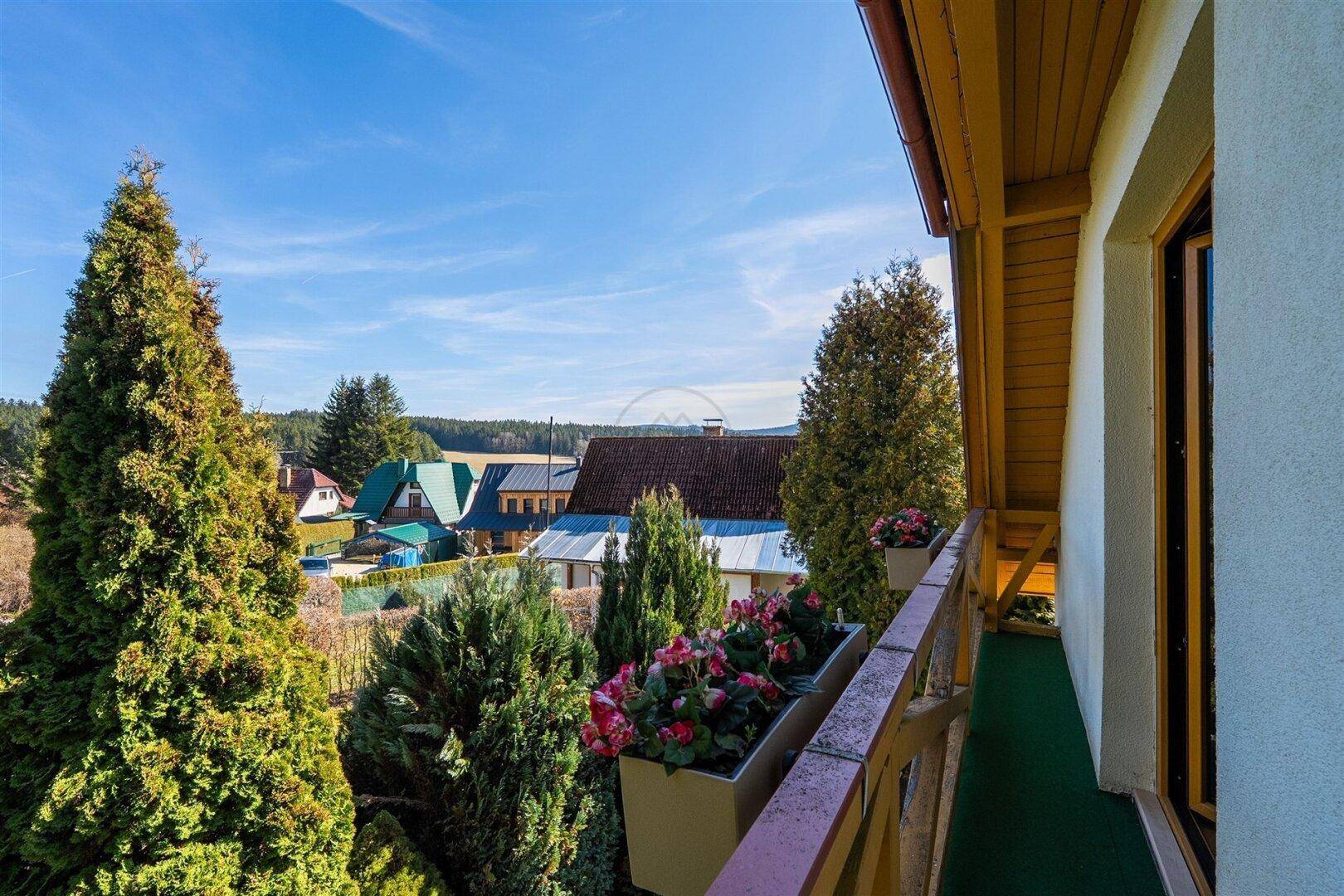 Kleiner Balkon mit Blumenkästen und Blick auf die umliegende Siedlung und Landschaft.