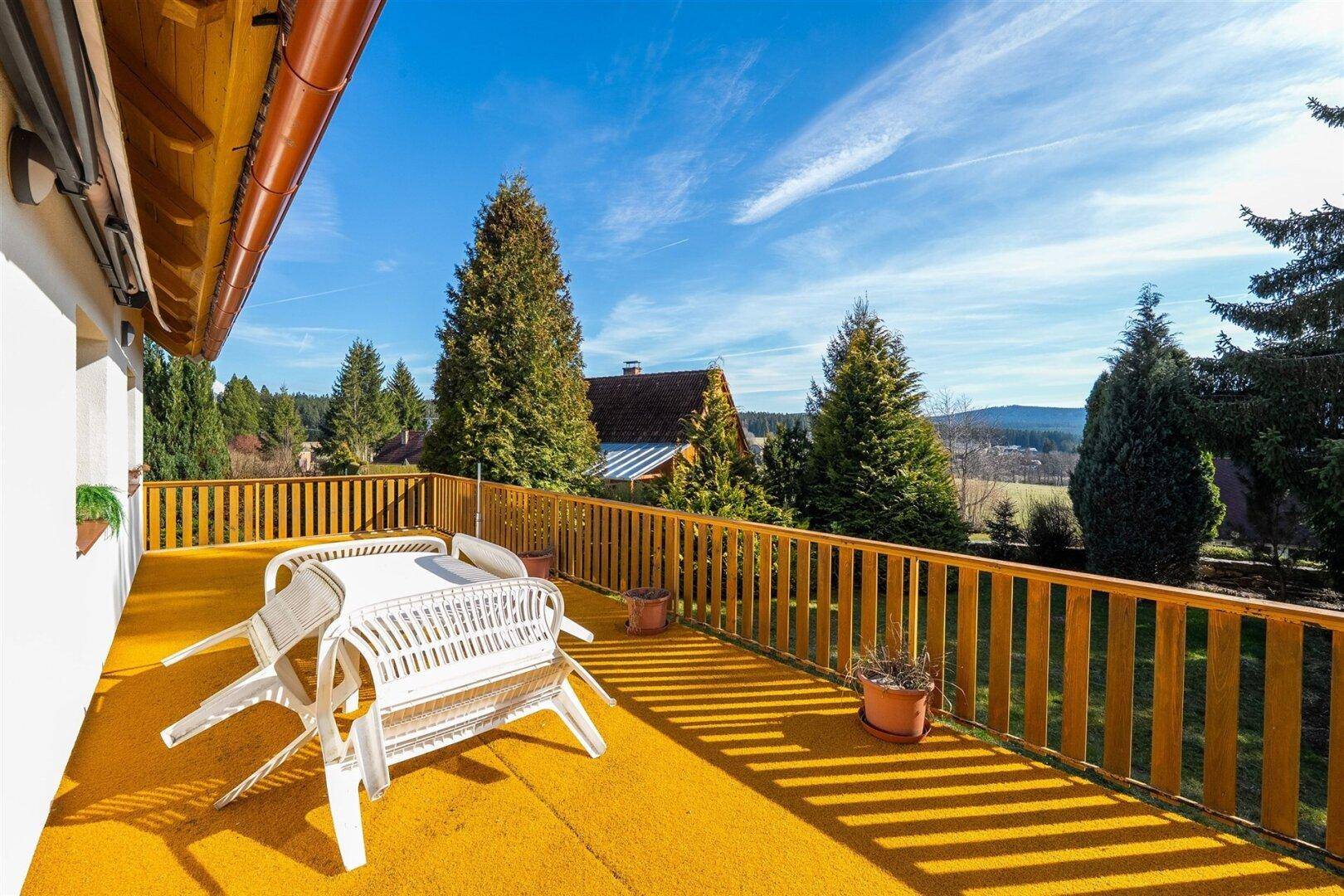 Sonnige Terrasse mit Gartenmöbeln und weitem Blick über die Landschaft.