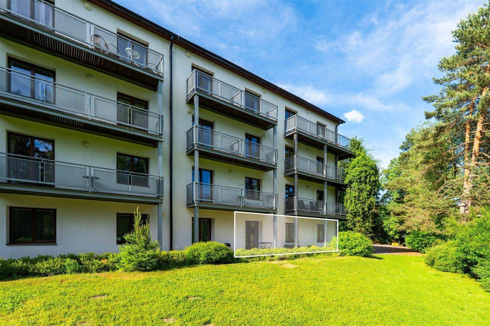 Fassade des modernen Wohngebäudes mit mehreren Balkonen und gepflegter Rasenfläche.