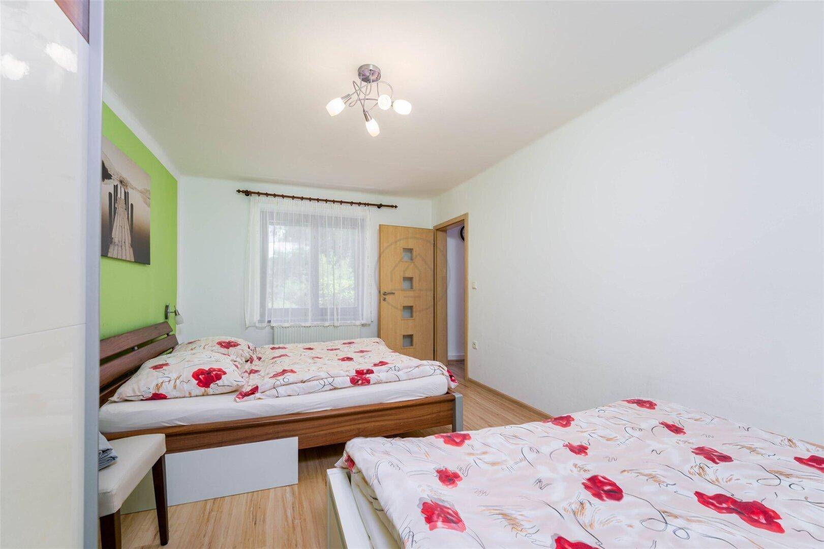 Schlafzimmer mit Fenster, das viel Tageslicht hereinlässt, und Zugang zu einem weiteren Raum.