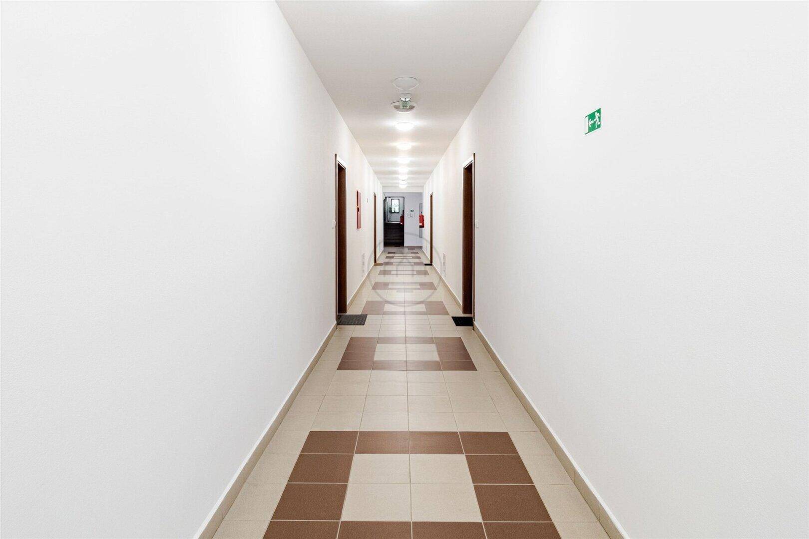 Langer, heller Flur mit Fliesenboden und mehreren Türen zu den Wohneinheiten.