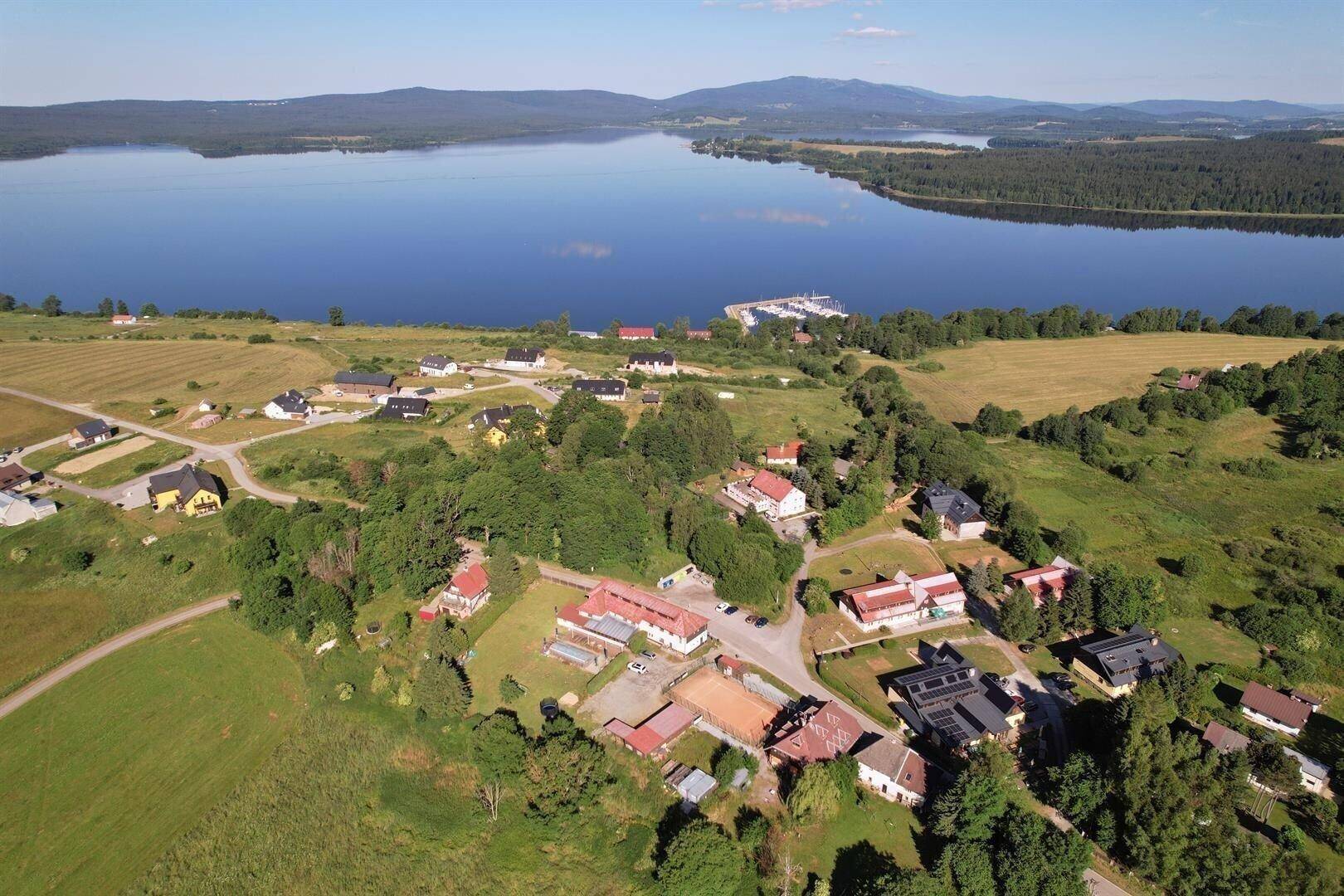 Weitläufige Luftaufnahme der Landschaft mit großem See, Wäldern und Bergen im Hintergrund.