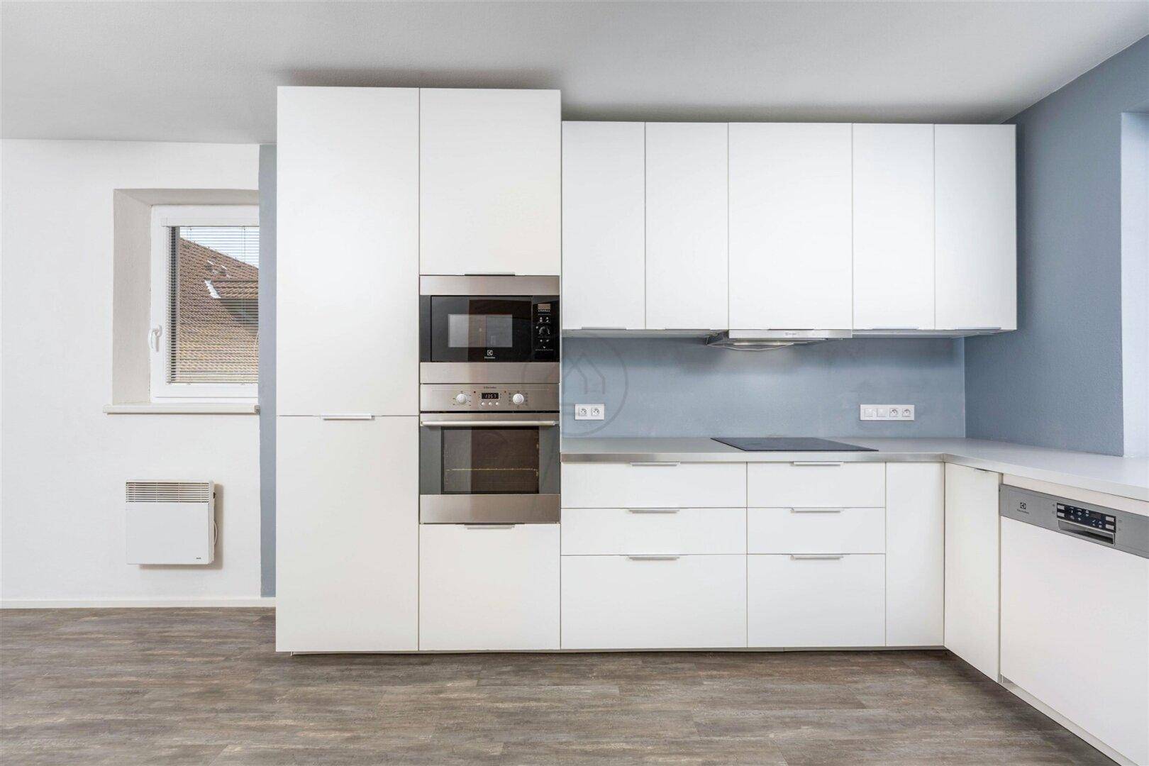 Helle, moderne Einbauküche in Weiß mit Induktionskochfeld und integrierten Backöfen.