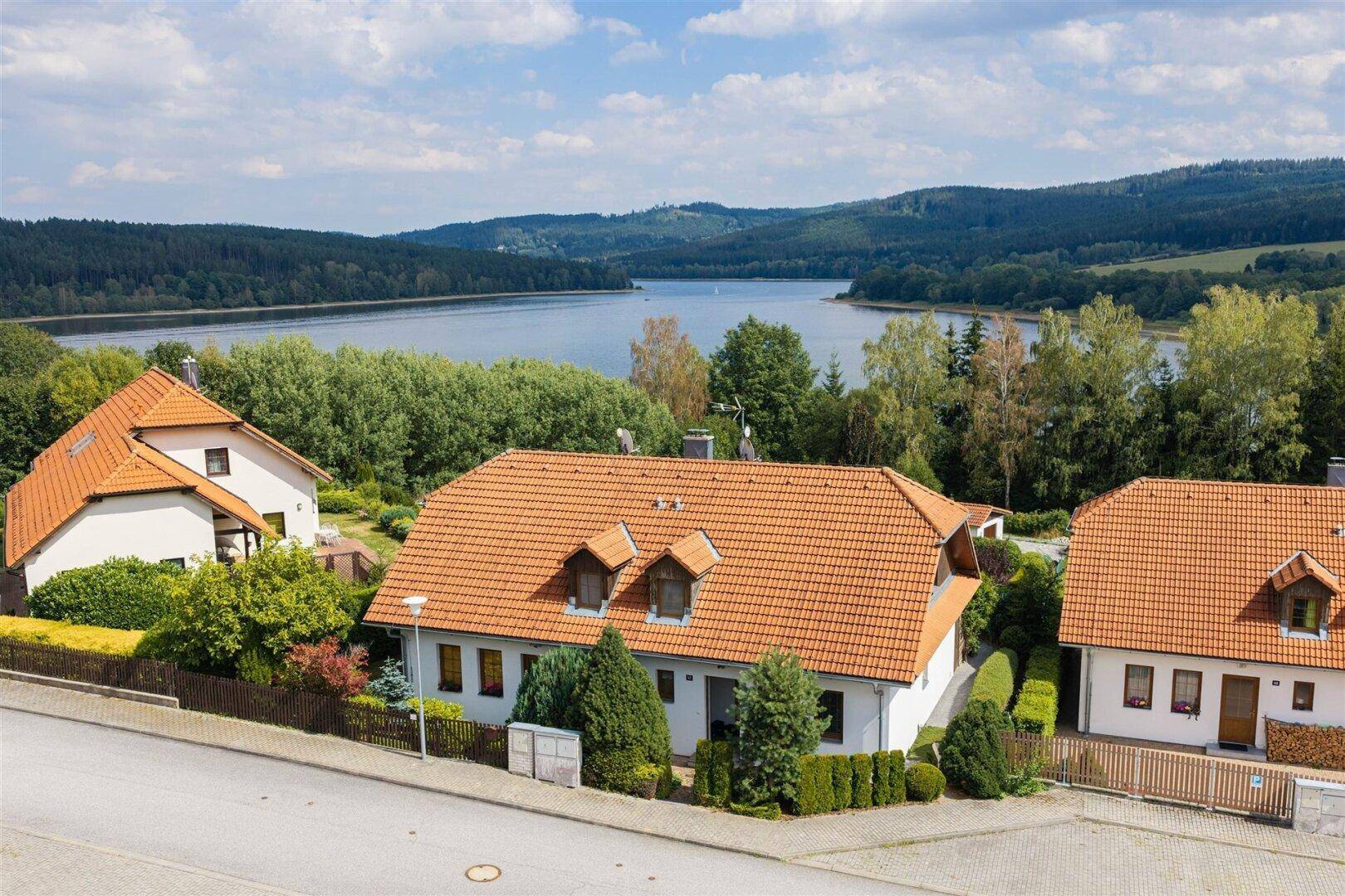 Häuserzeile mit roten Ziegeldächern und weitem Blick auf den See und die umliegende Landschaft.