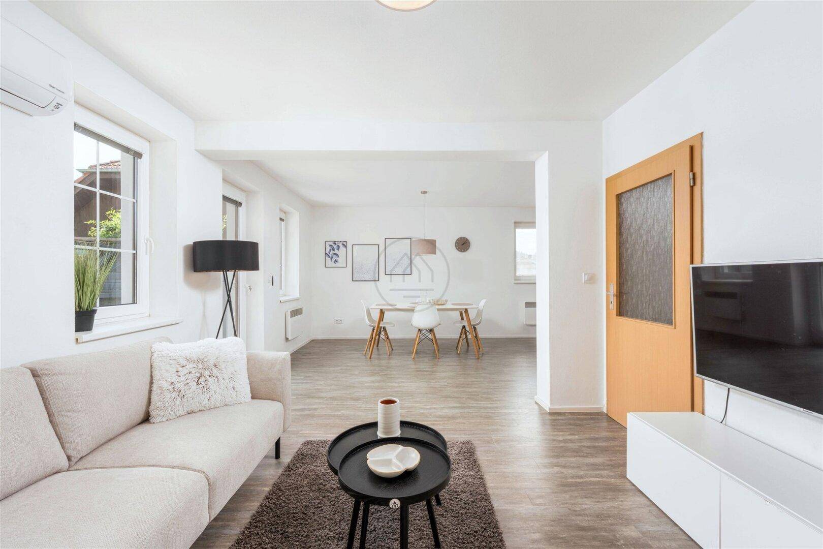 Helles Wohnzimmer mit beigem Sofa, modernem Couchtisch und offenem Übergang zum Essbereich.