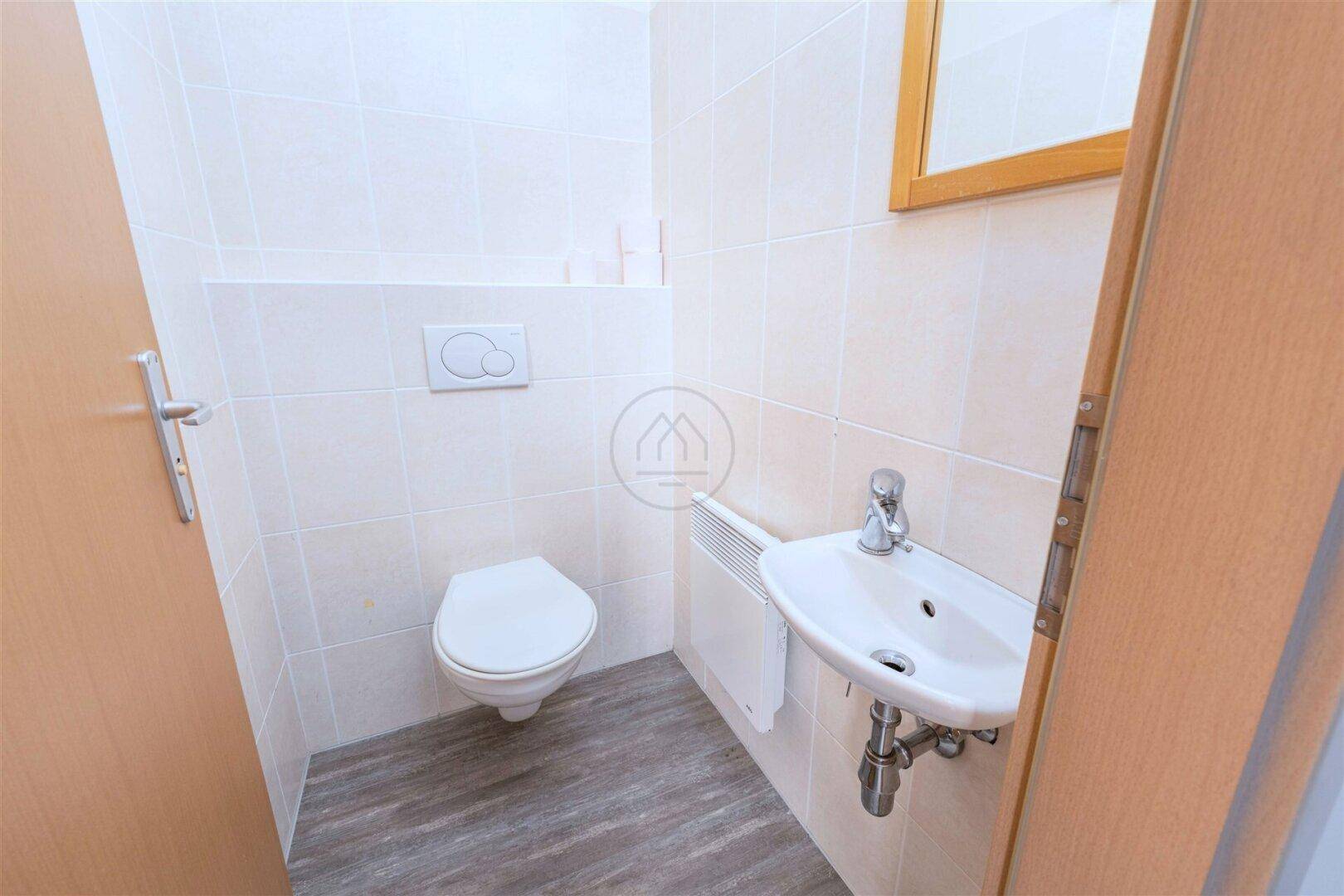 Kleines Gäste-WC mit wandhängendem WC und Handwaschbecken, modern gefliest.