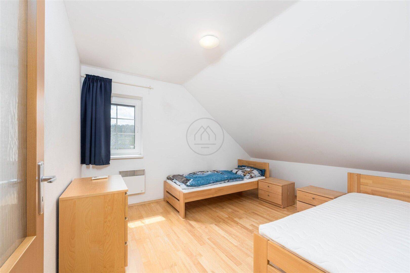 Gemütliches Schlafzimmer im Dachgeschoss mit Holzboden, Einzelbetten und Fenster mit Ausblick.