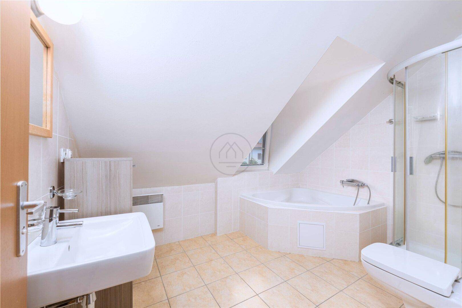 Helles Badezimmer im Dachgeschoss mit Eckbadewanne, Dusche und schrägen Wänden.