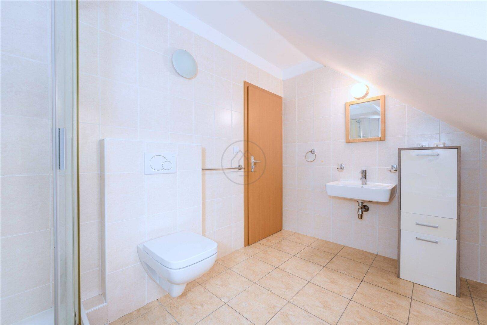 Modernes Badezimmer mit Dusche, wandhängendem WC und Waschbecken, hell gefliest.