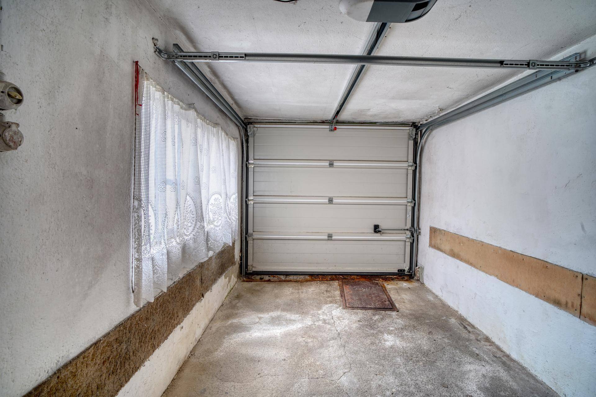 Einzelgarage mit Rolltor und Betonboden, bietet Platz für ein Fahrzeug.