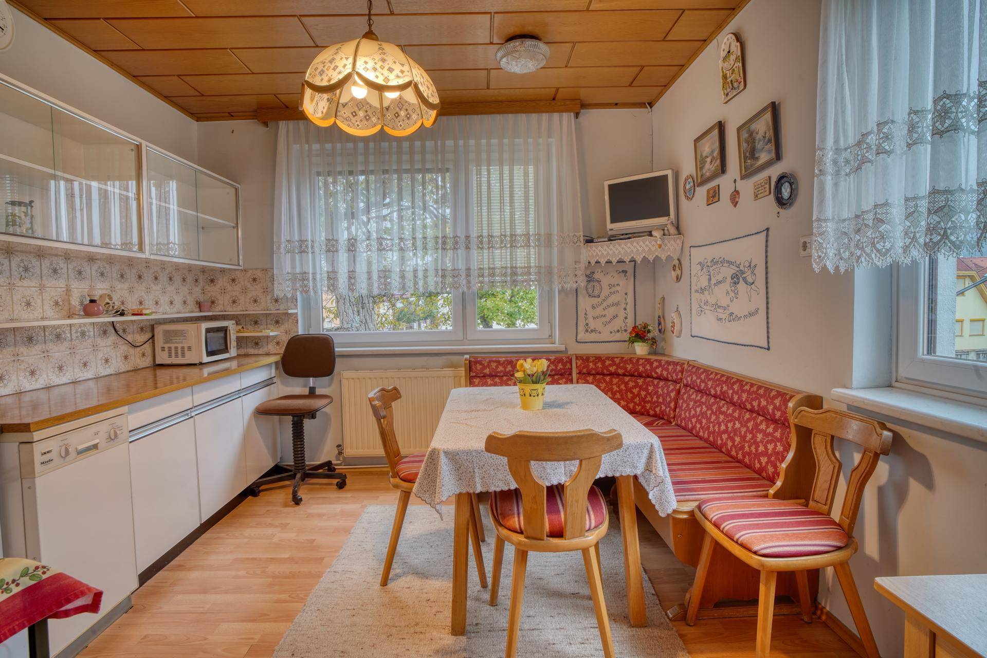 Gemütliche Wohnküche mit Essecke, Einbauküche und Holzdecke im Landhausstil.
