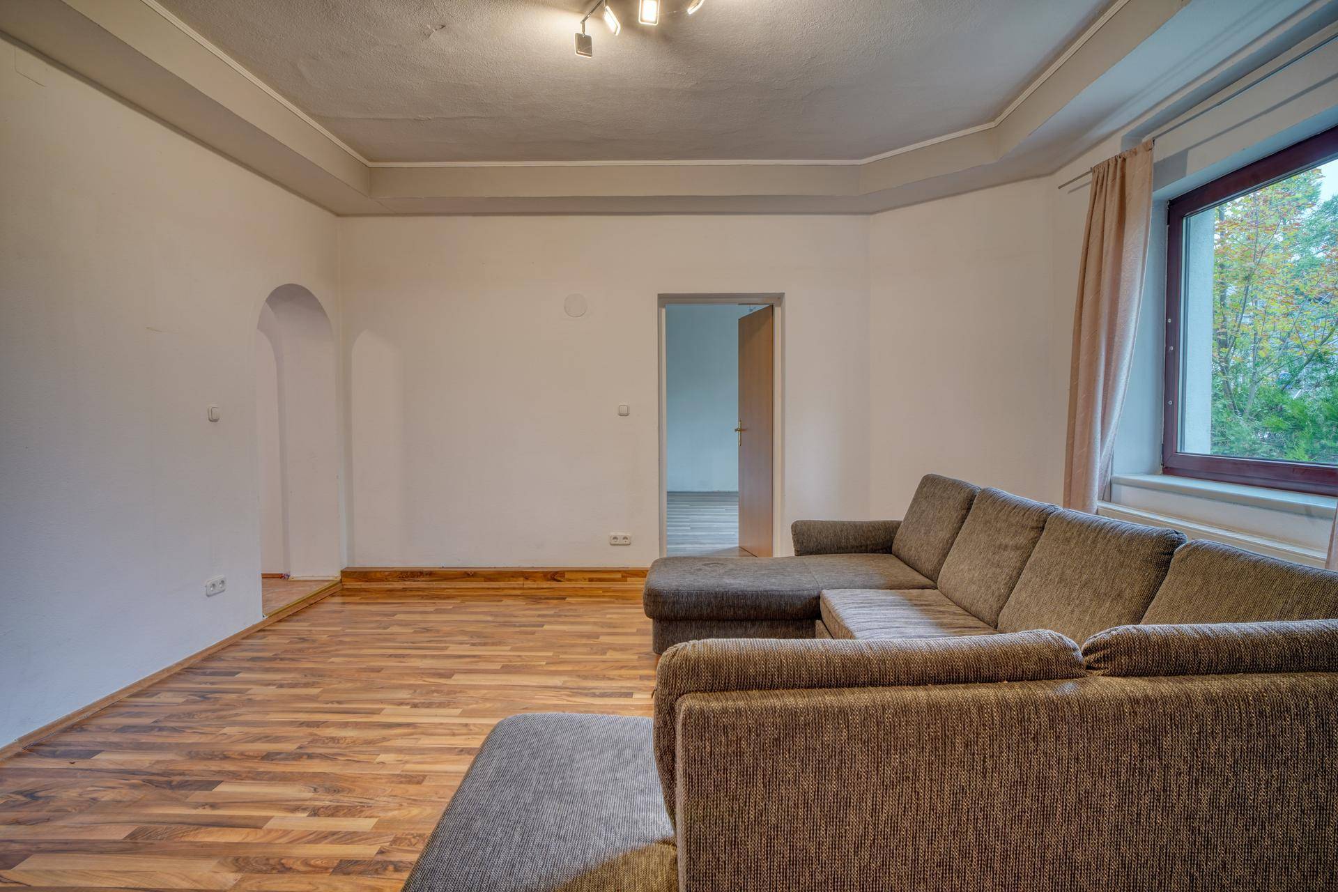Gemütliches Wohnzimmer mit Parkettboden, bequemer Couch und Blick ins Grüne.