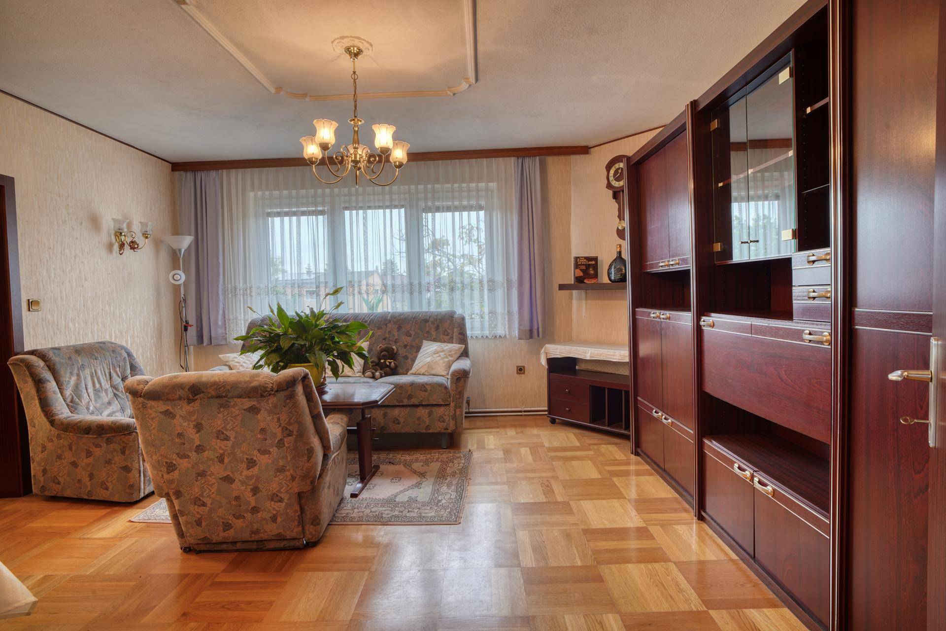 Geräumiges Wohnzimmer mit Parkettboden, bequemen Sofas und einem großen Holzschrank.