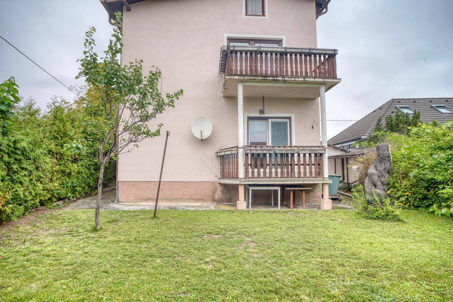 Rückseite des Hauses mit zwei Balkonen und Zugang zum grünen Gartenbereich.