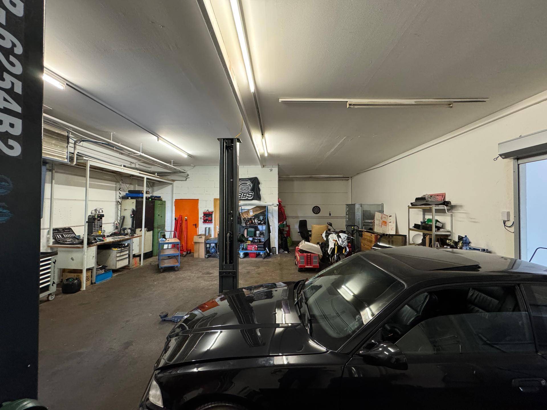 Helle Werkstatt mit professioneller Ausstattung, inklusive Hebebühne und Arbeitsbereichen.