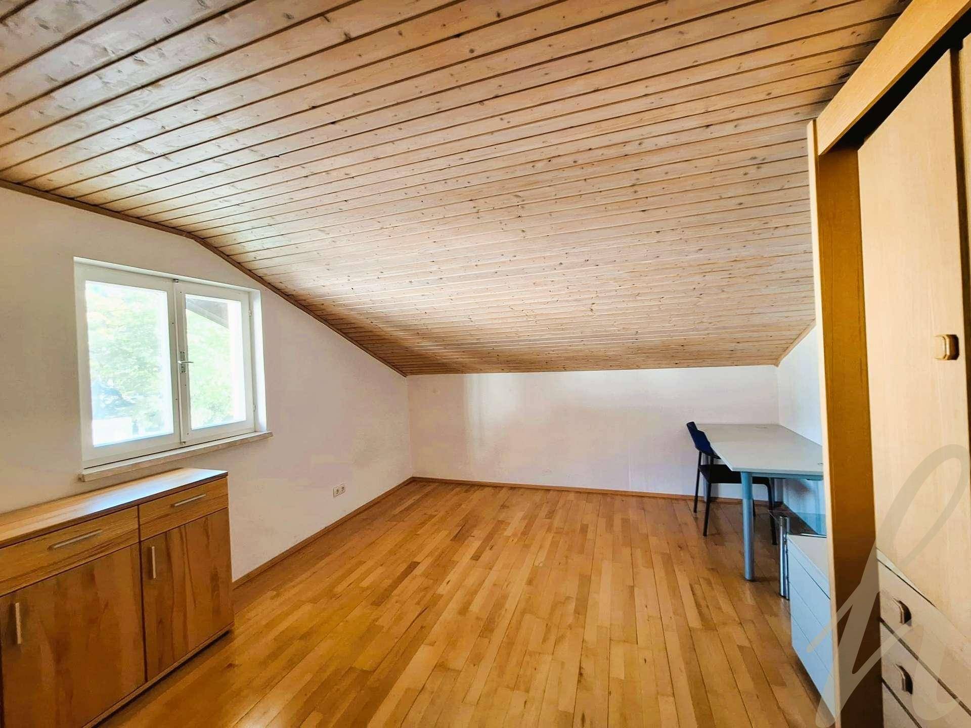 Geräumiger Dachbodenraum mit Holzdecke, Holzboden und Fenster, ideal als Schlaf- oder Arbeitszimmer.