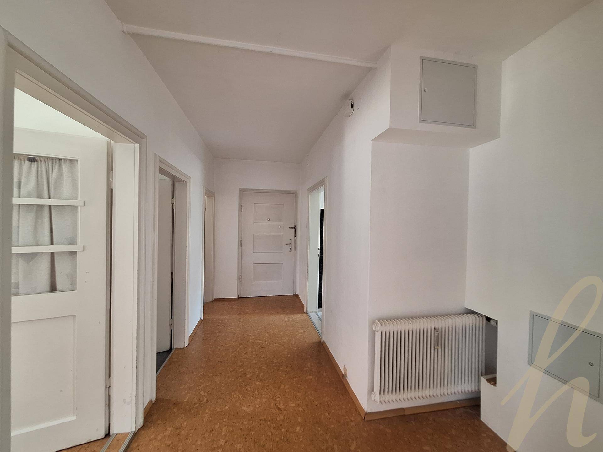 Heller Flur mit Laminatboden und weiß gestrichenen Wänden, der zu weiteren Räumen führt.