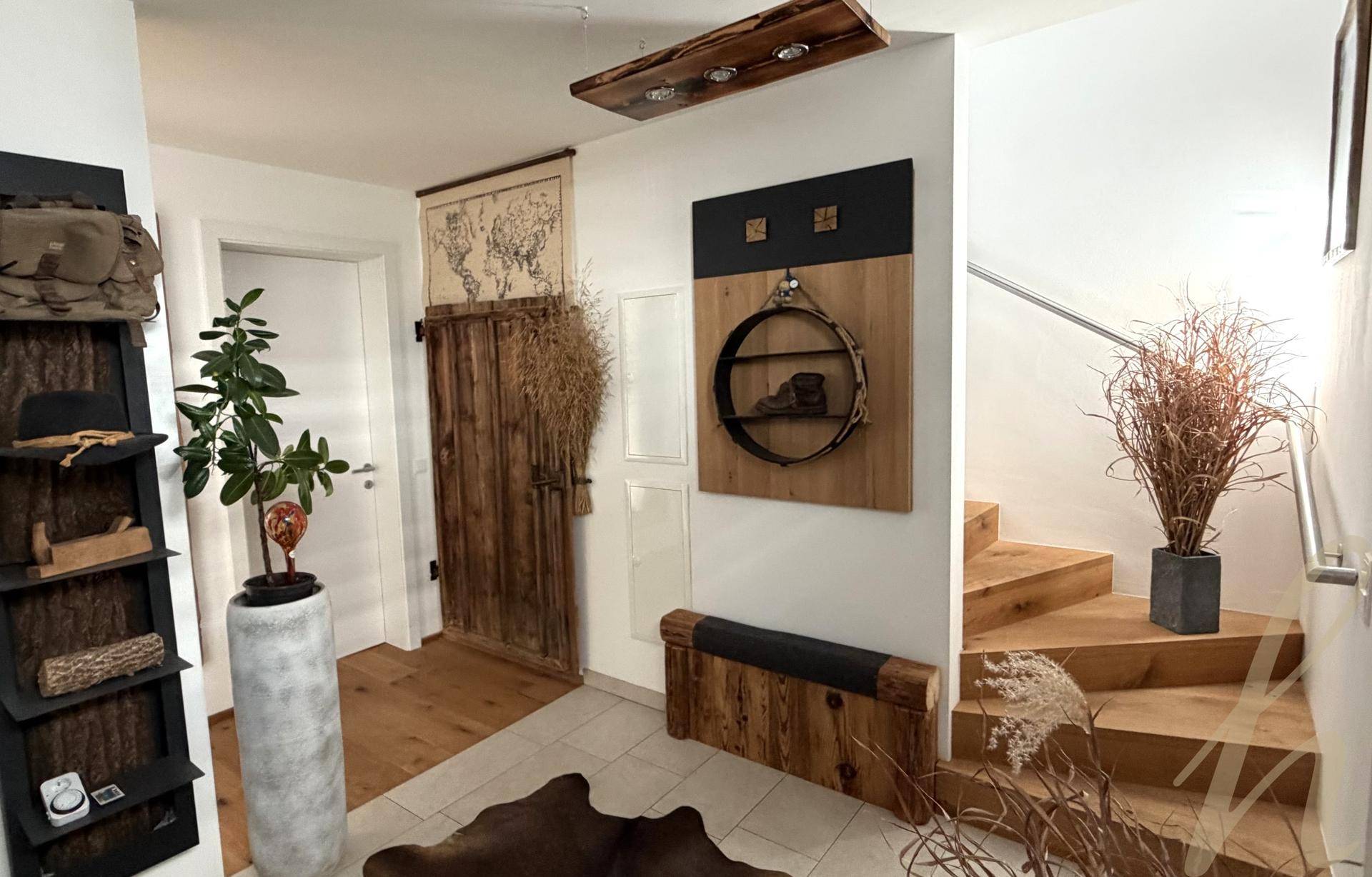 Eingangsbereich mit Holztreppe und rustikalen Dekorationselementen, führt in die obere Etage.