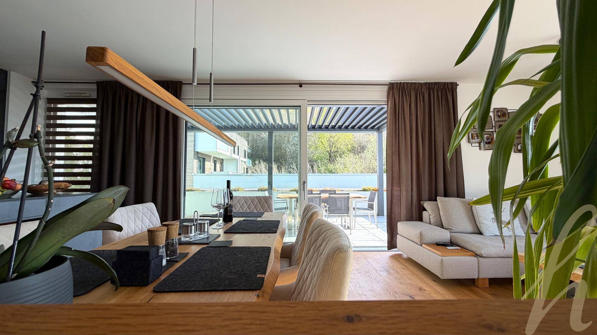 Heller Wohn- und Essbereich mit Holzboden und direktem Zugang zu einer überdachten Terrasse.
