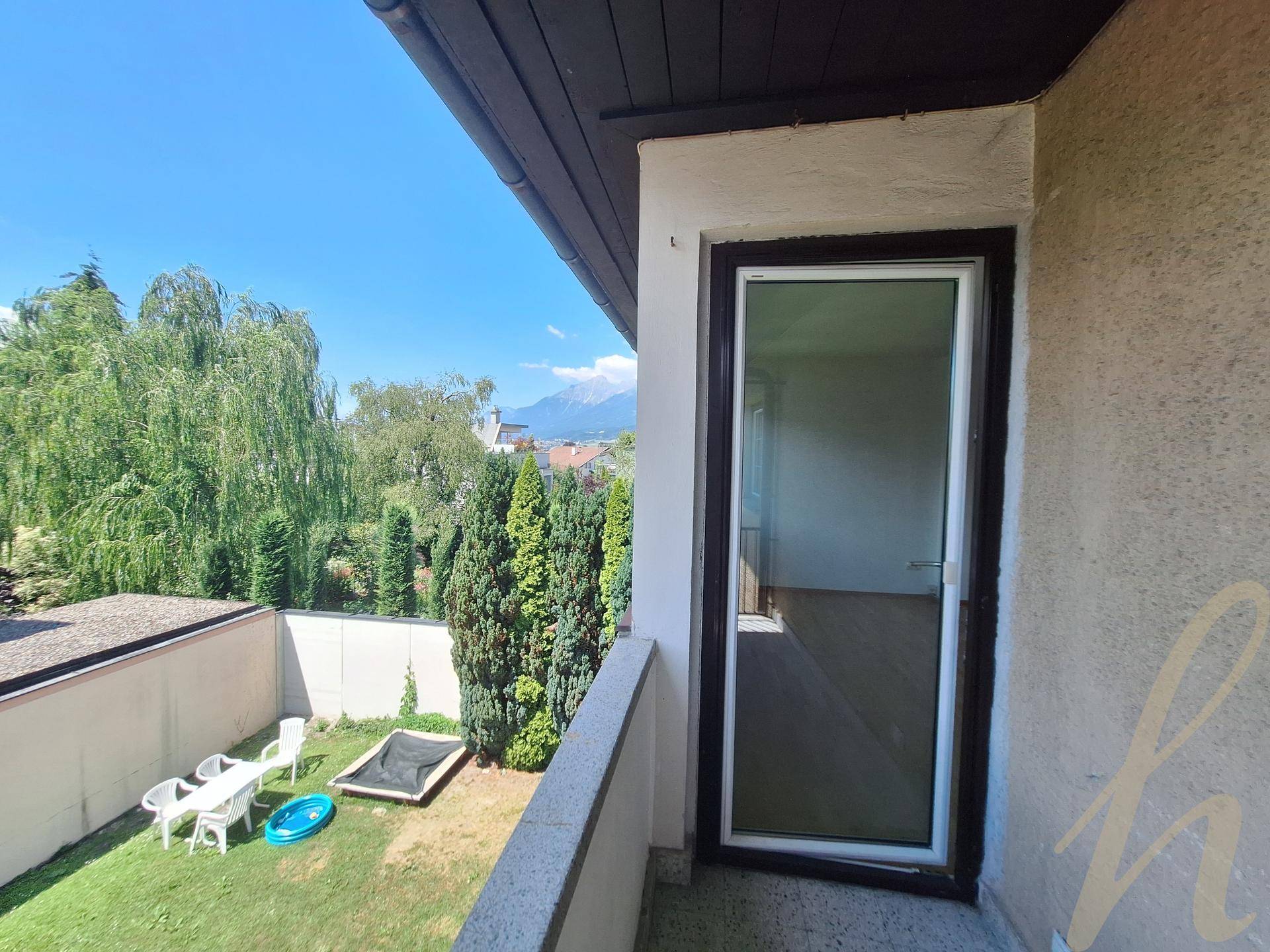 Balkon mit Blick auf den Garten und die umliegende grüne Landschaft.