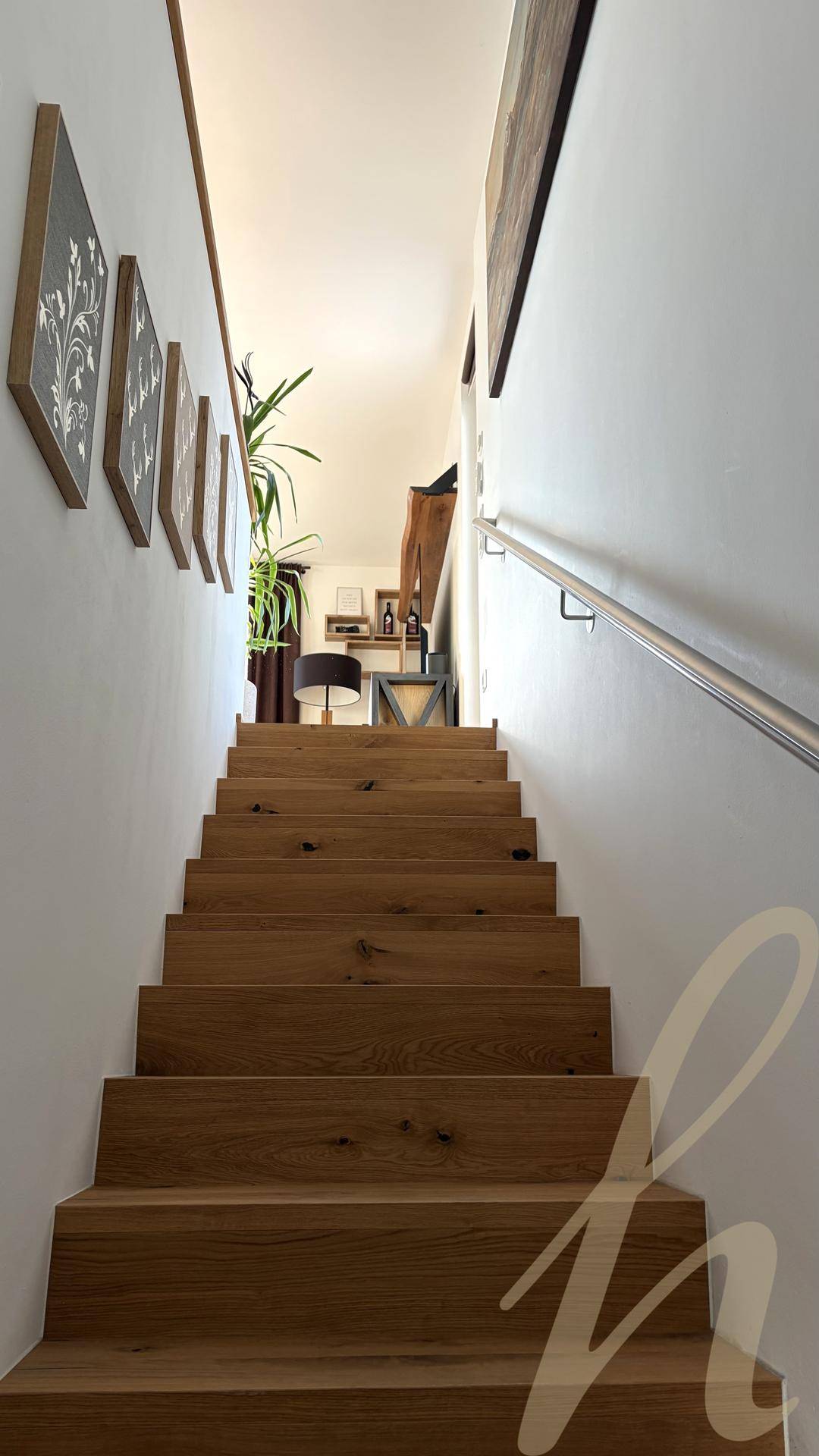Holztreppe mit schlichtem Geländer, führt zu den oberen Wohnbereichen.