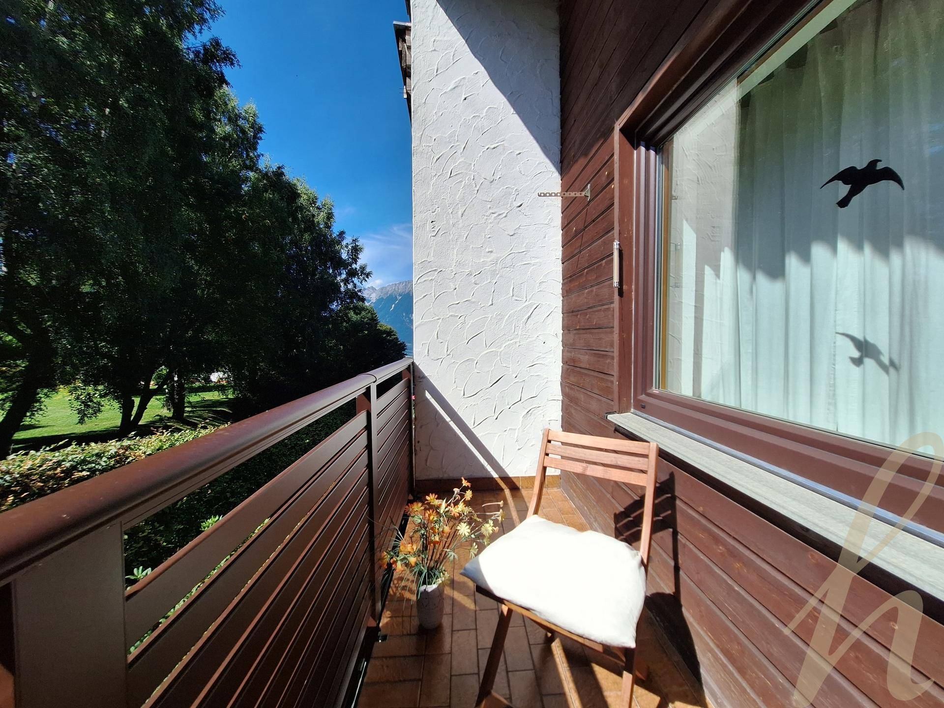 Kleiner Balkon mit Stuhl und Topfpflanze, bietet einen schönen Blick auf Bäume und Berge.