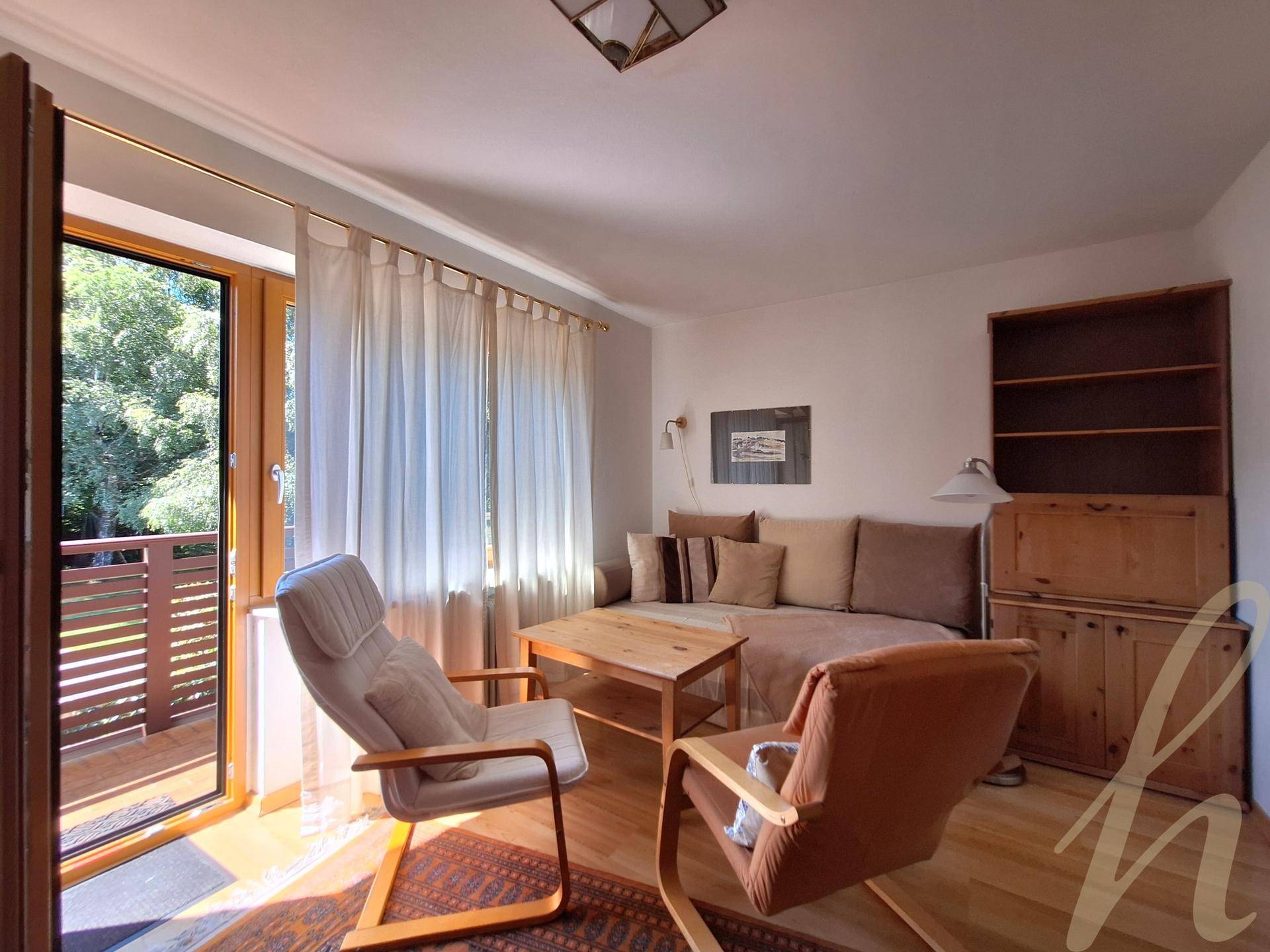 Gemütliches Wohnzimmer mit Sofa, Sesseln und direktem Zugang zu einem sonnigen Balkon.