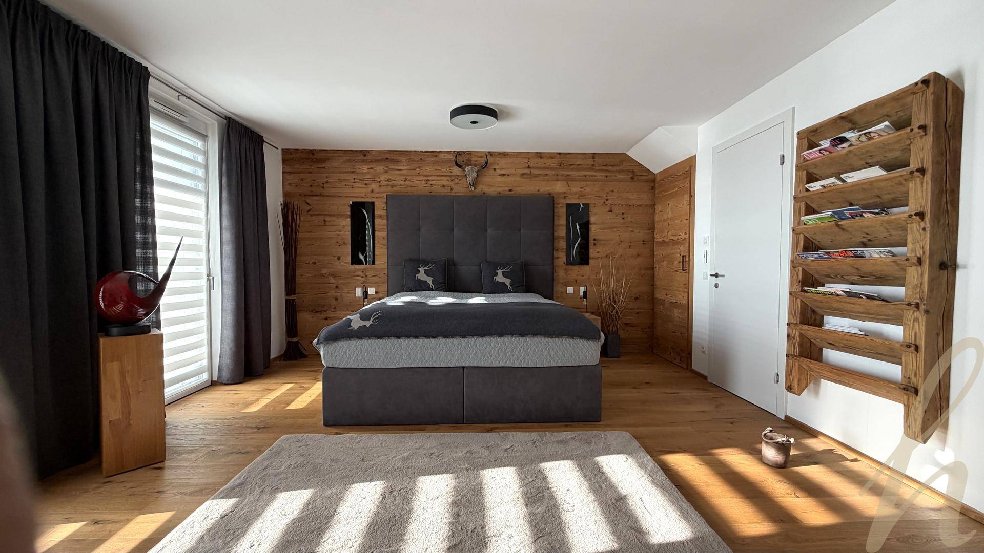 Schlafzimmer mit Holzwand als Akzent, großem Bett und rustikalen Dekorationselementen.