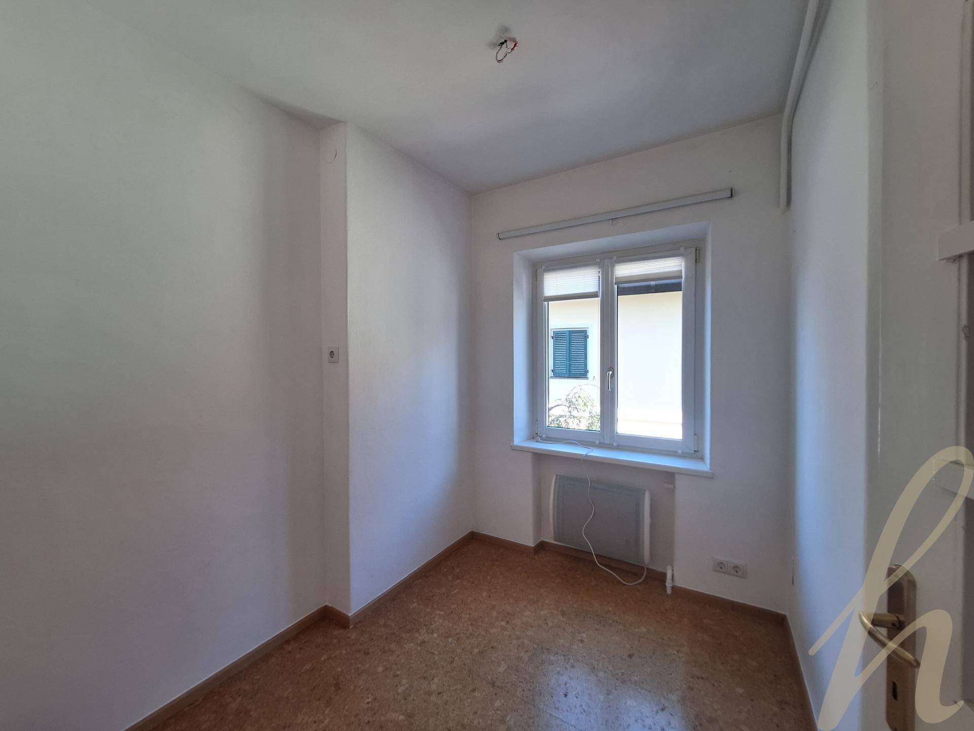 Kleines Zimmer mit Laminatboden und einem Fenster, das viel natürliches Licht hereinlässt.