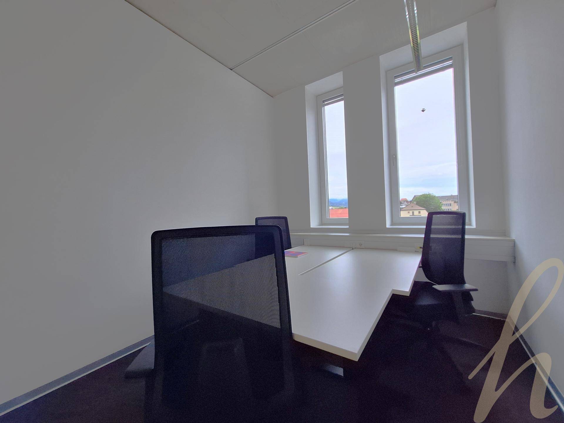 Büroarbeitsplatz mit zwei Stühlen und Schreibtisch direkt am Fenster, bietet gute Beleuchtung und Ausblick.