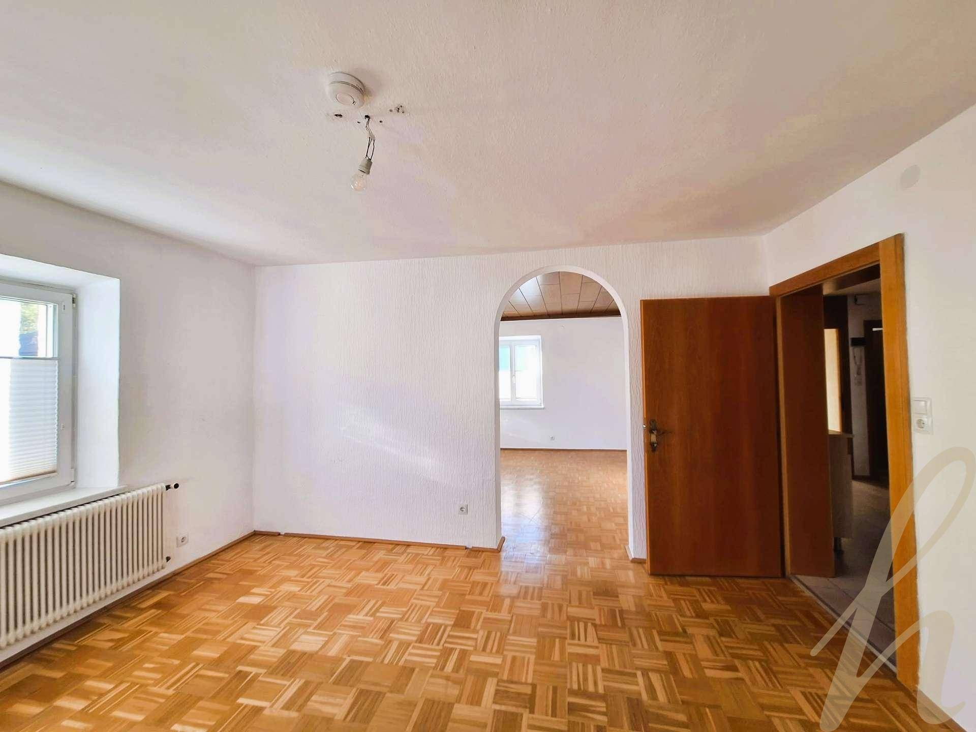 Helles Wohnzimmer mit Parkettboden, weiß gestrichenen Wänden und Rundbogen zum Nebenraum.