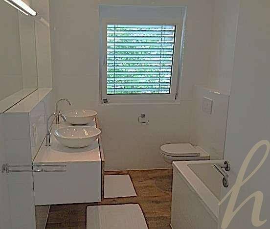 Modernes Badezimmer mit Badewanne, Doppelwaschbecken und einem Fenster für natürliche Belüftung.