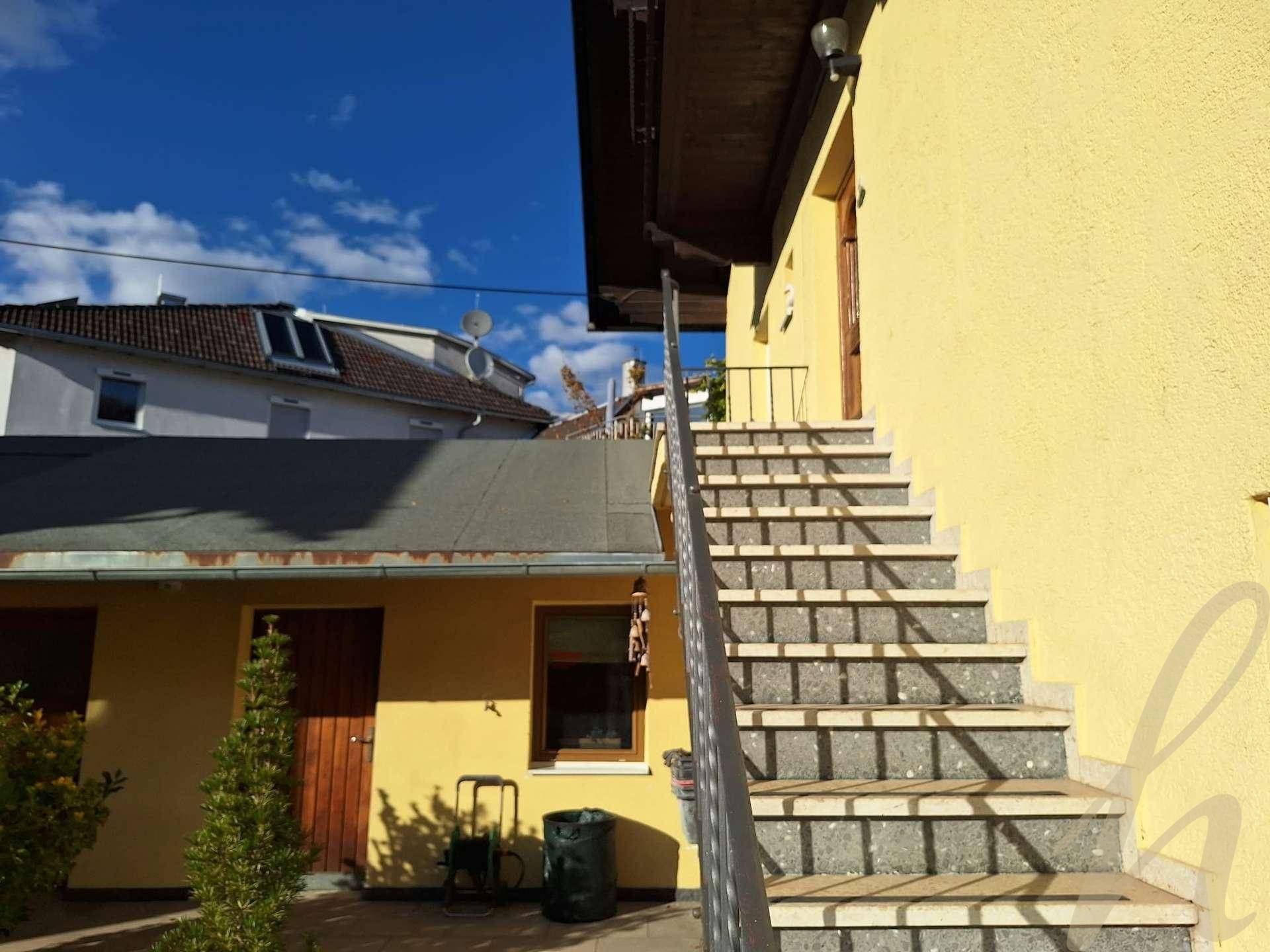 Außenansicht eines gelben Gebäudes mit einer Steintreppe unter blauem Himmel.